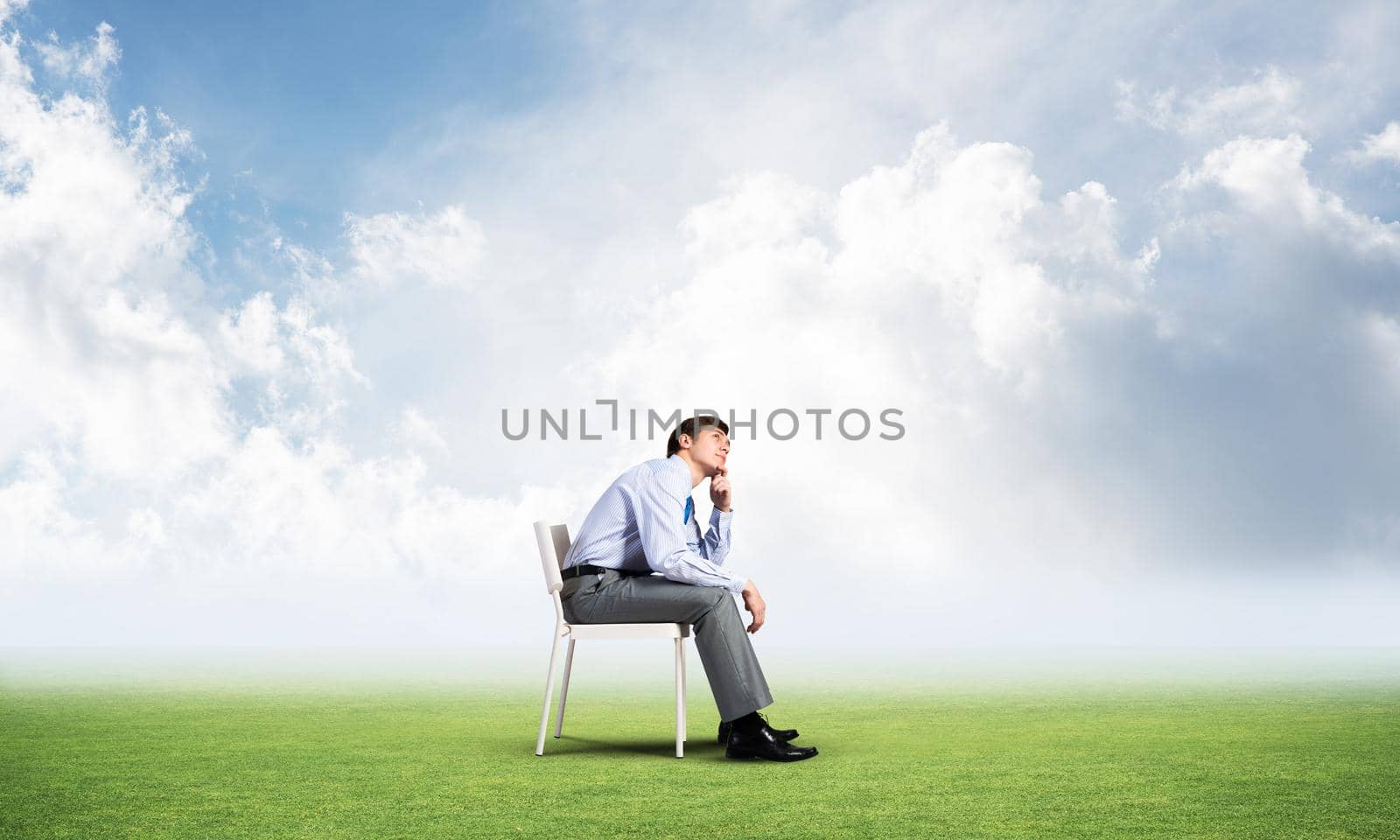 young businessman sits on an office chair, thoughtful and looking up