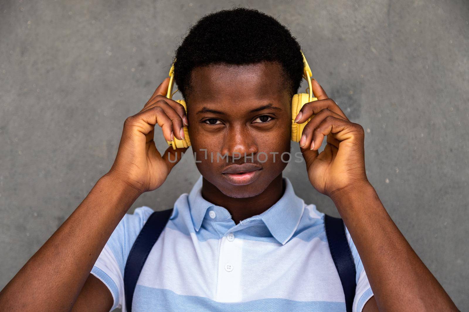 Teenage African American boy looking at camera holding headphones with hands. Lifestyle concept.