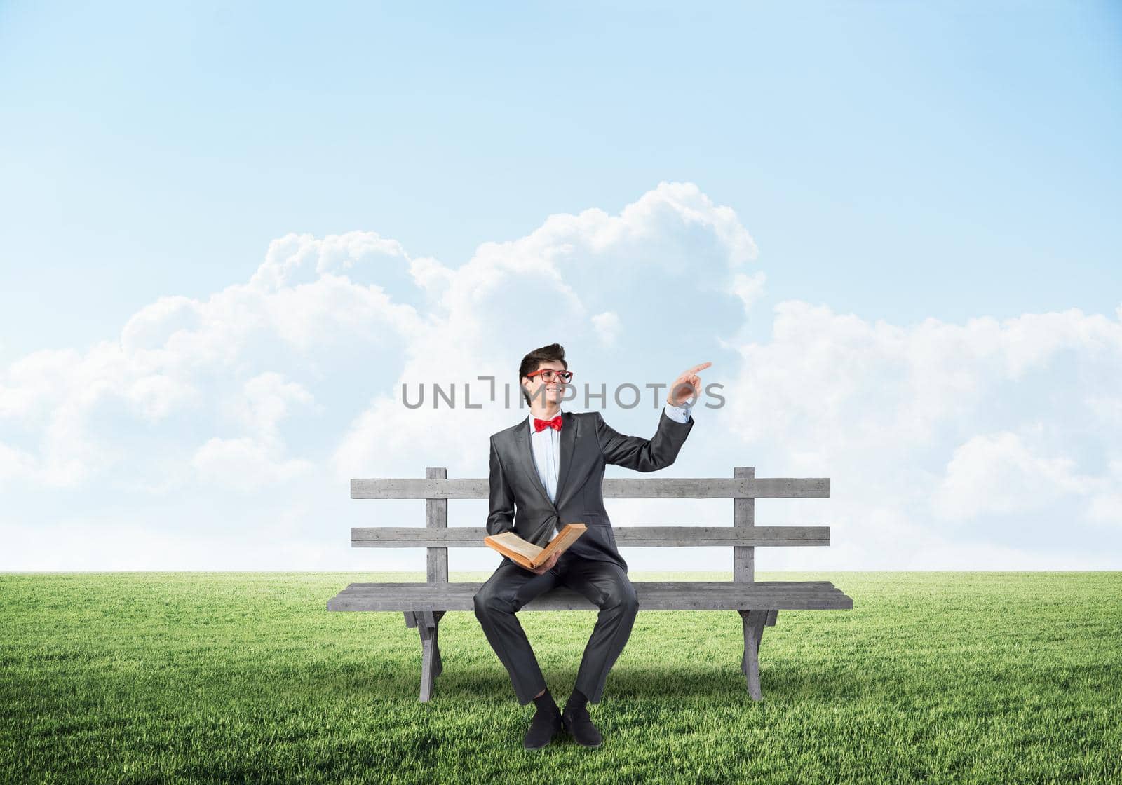 young student with a book. sits on a wooden bench