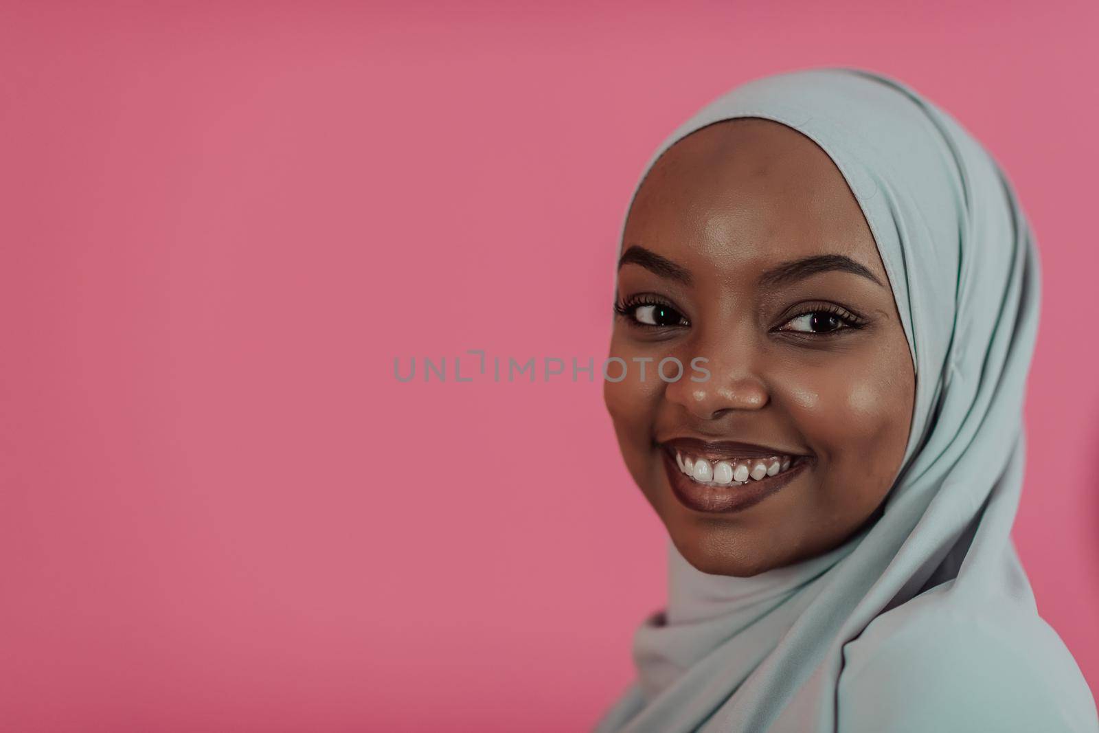 Portrait of young modern muslim afro beauty wearing traditional islamic clothes on plastic pink background. Selective focus. High quality photo