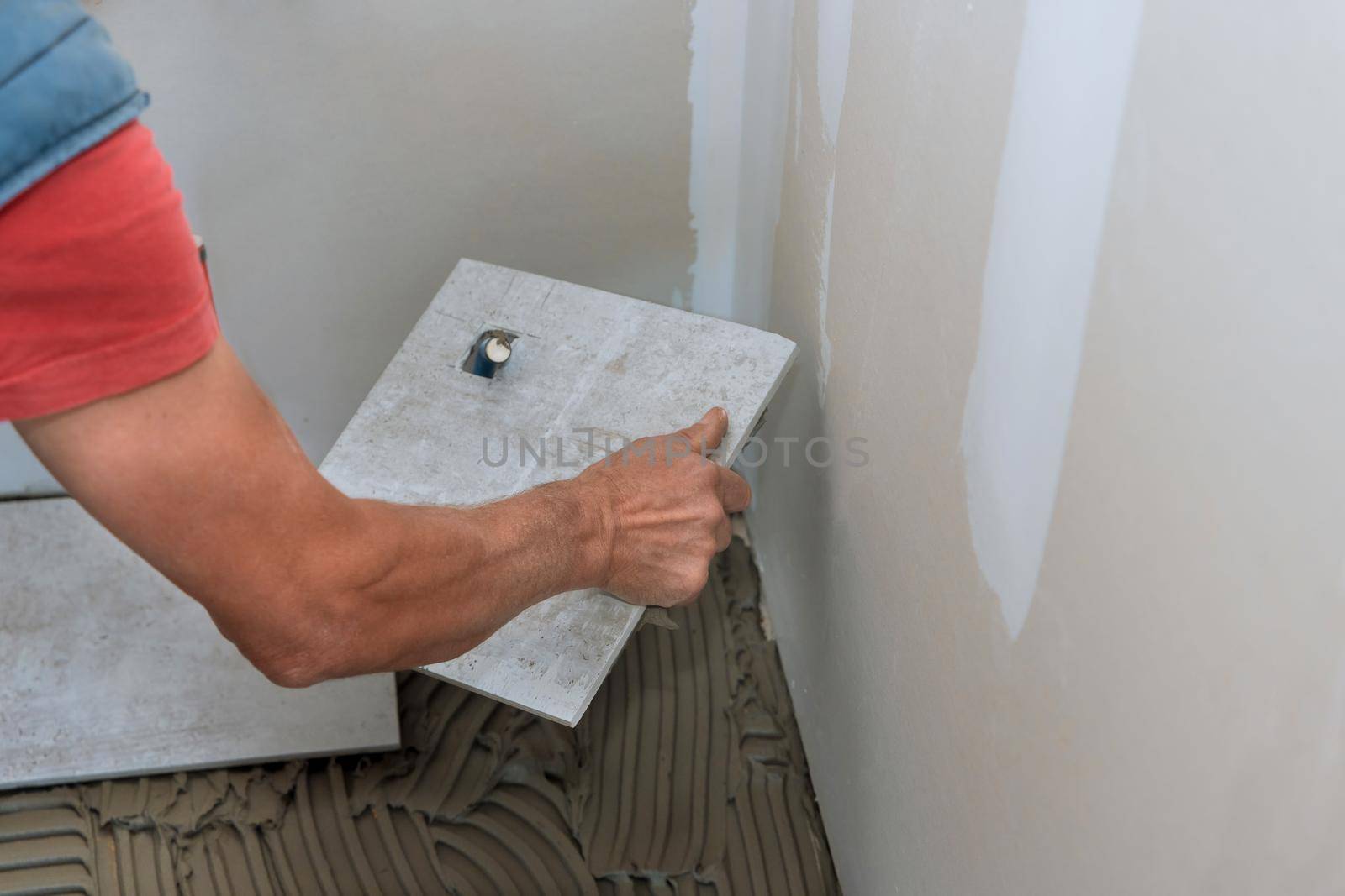 Workers hands with applying tile adhesive to the floor process on of laying ceramic tiles