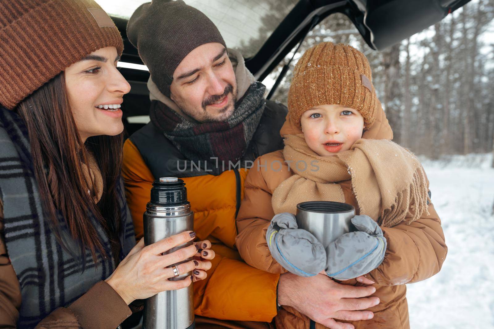 Winter portrait of a family sit on car trunk enjoy their vacation in forest by Fabrikasimf