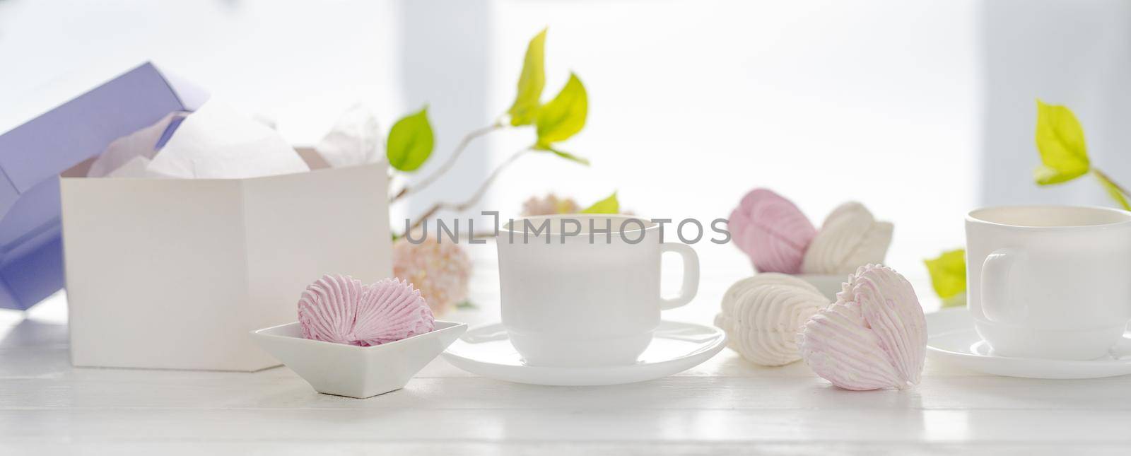 Heart shape marshmallows pink and white color and cups with tea. Craft desert sweets with beverage romantic composition for Valentine day