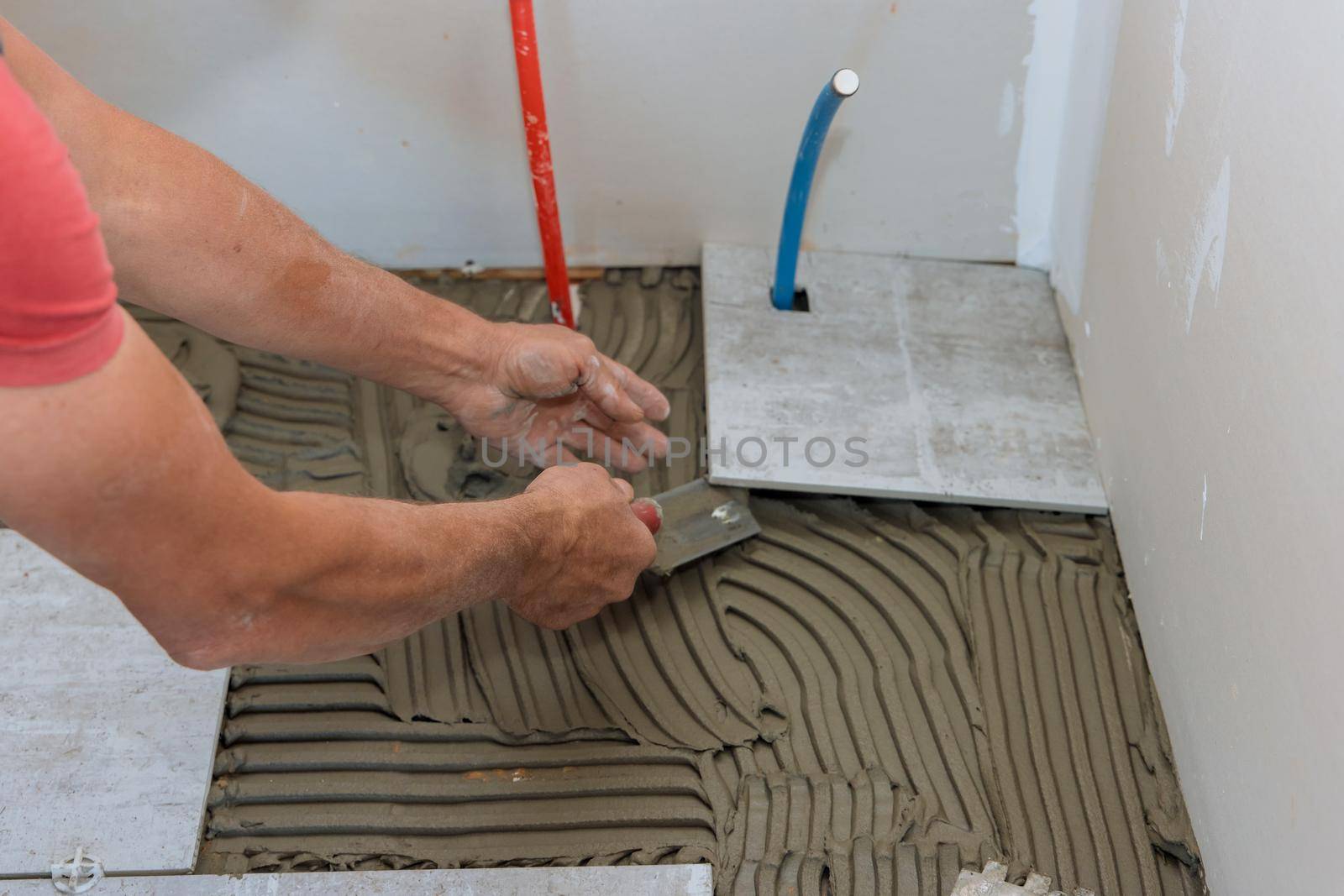 Man placing ceramic floor tile in position over adhesive in new home