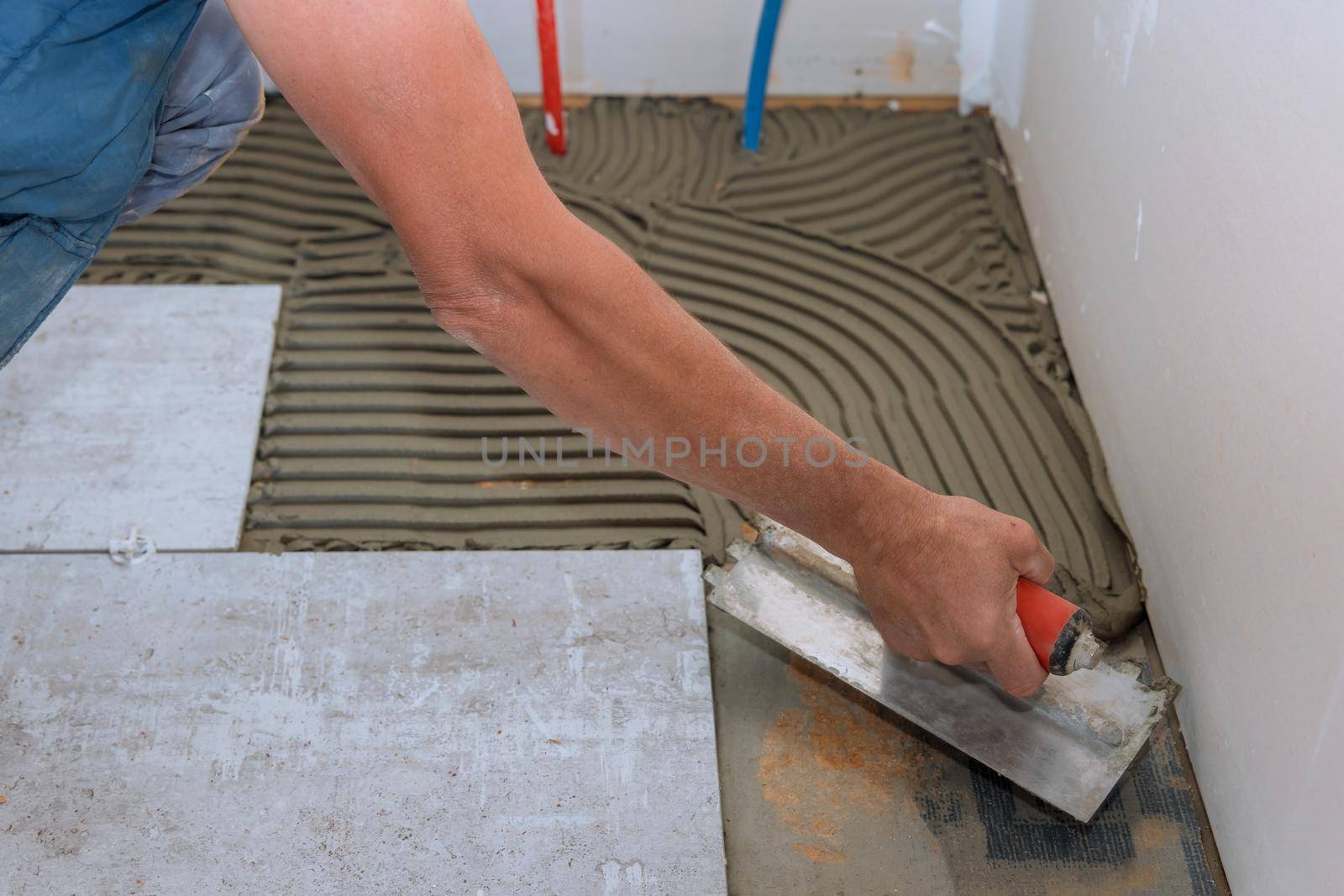 Man making using adhesive cement base the ceramic tile flooring