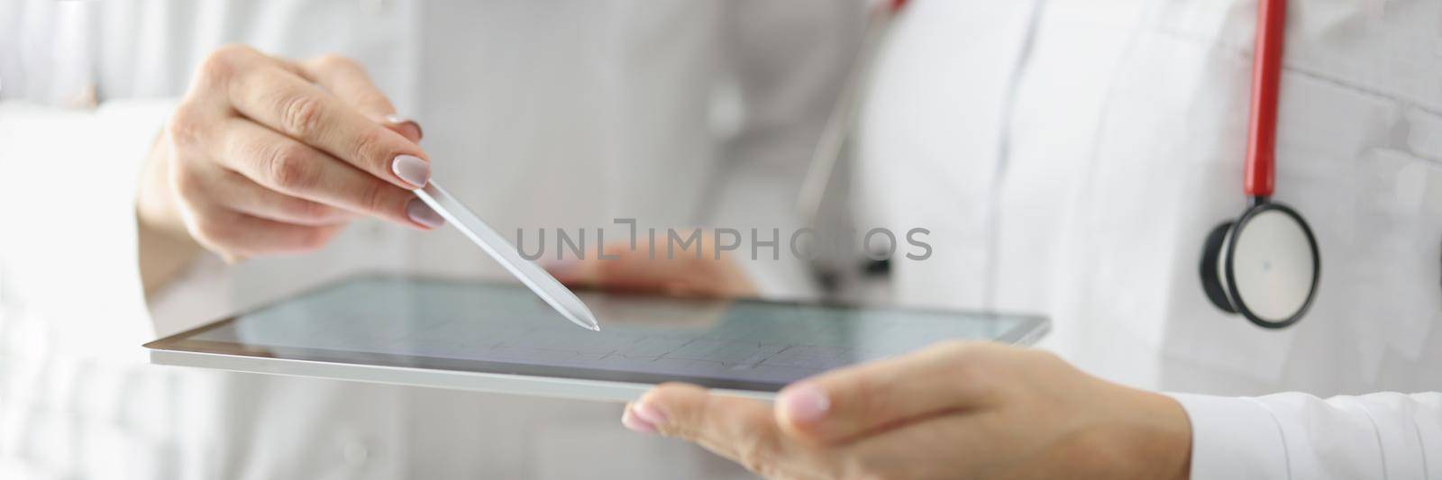 Close-up of doctor point with pen on tablet screen, result of echocardiogram on device. Professional medical worker discuss treatment. Medicine, checkup, cardiology, health concept. Blurred background