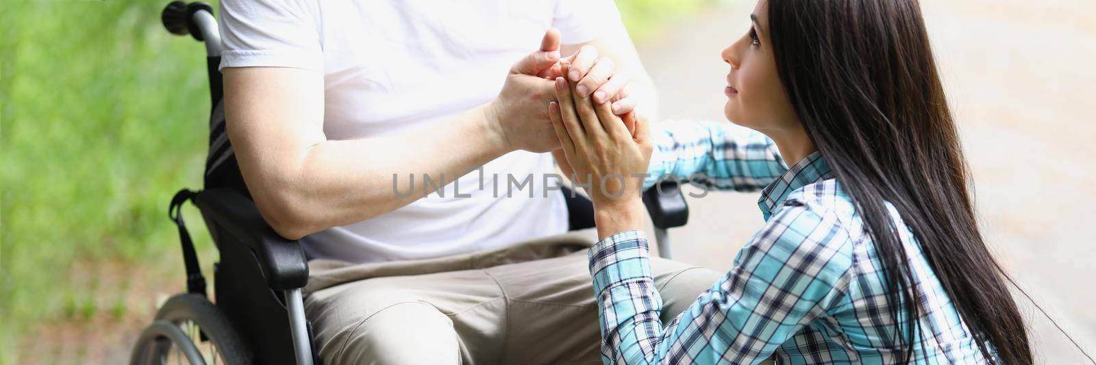 Portrait of young woman comforting man in wheelchair, assure him in sooner recovery. Female hold husband hand. Healthcare, accident, injury, family, relationship, support concept