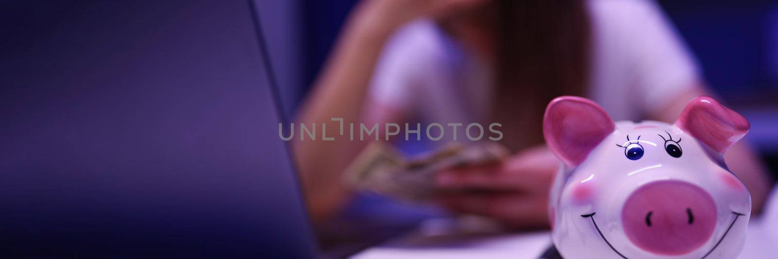 Close-up of piggy bank on desk, broken woman count money on background. Saving up for tomorrow, pay bills, invest. Finance, planning budget, economy, family banking concept. Blurred background