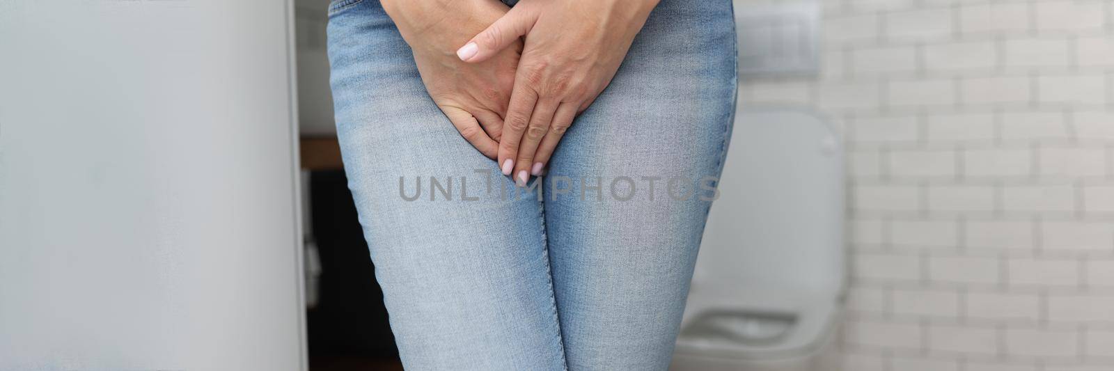 Close-up of woman with natural need to pee, incontinence, nature call. Female close lower body with hands, cant stand. Bathroom, toilet, hygiene, restroom, wc concept. Blurred background