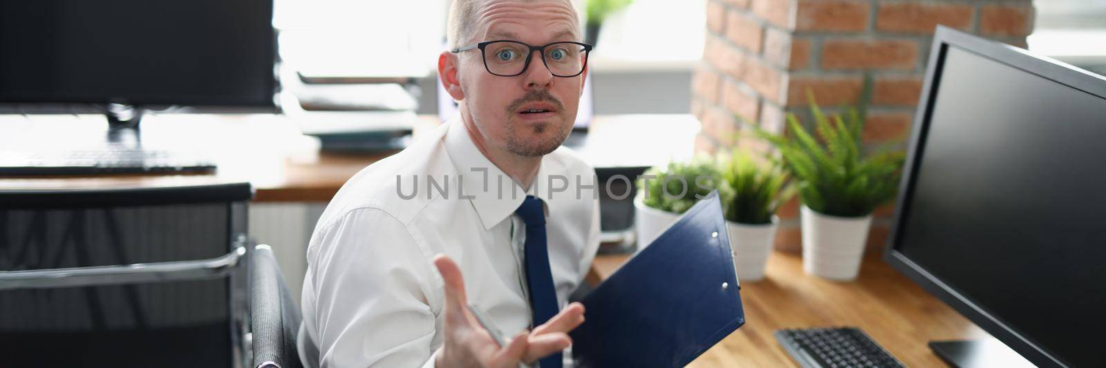 Portrait of employee with mixed emotions, loaded with work, stressed with paperwork. Man in suit on workplace, hard working all day, no break for lunch. Business, job concept