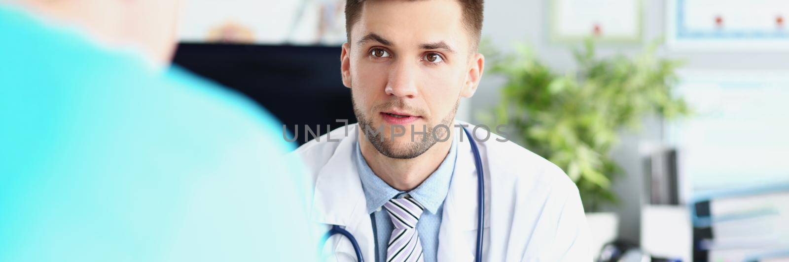 Portrait of young male doctor in uniform and stethoscope, work meeting in head doctor office. Listen to instructions of professional specialist, plan for work. Hospital, medicine concept