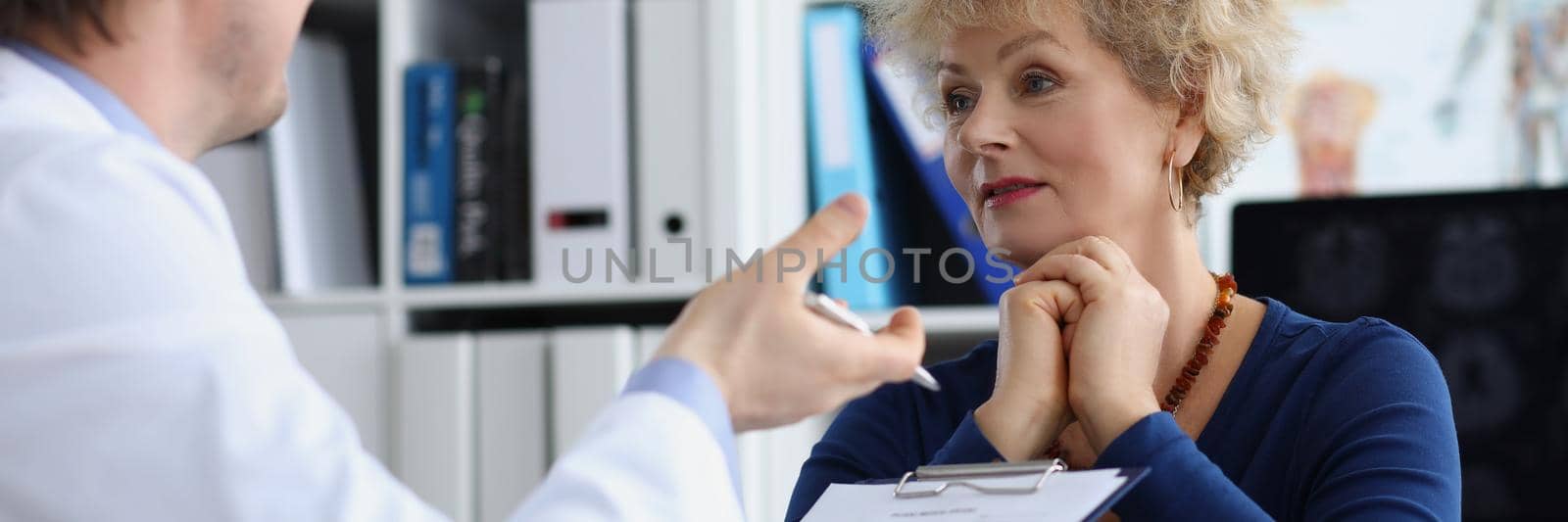Portrait of senior female on doctors appointment in clinic. Qualified doctor explains woman therapy for recovery, prescription for healing. Healthcare, modern medicine, hospital concept