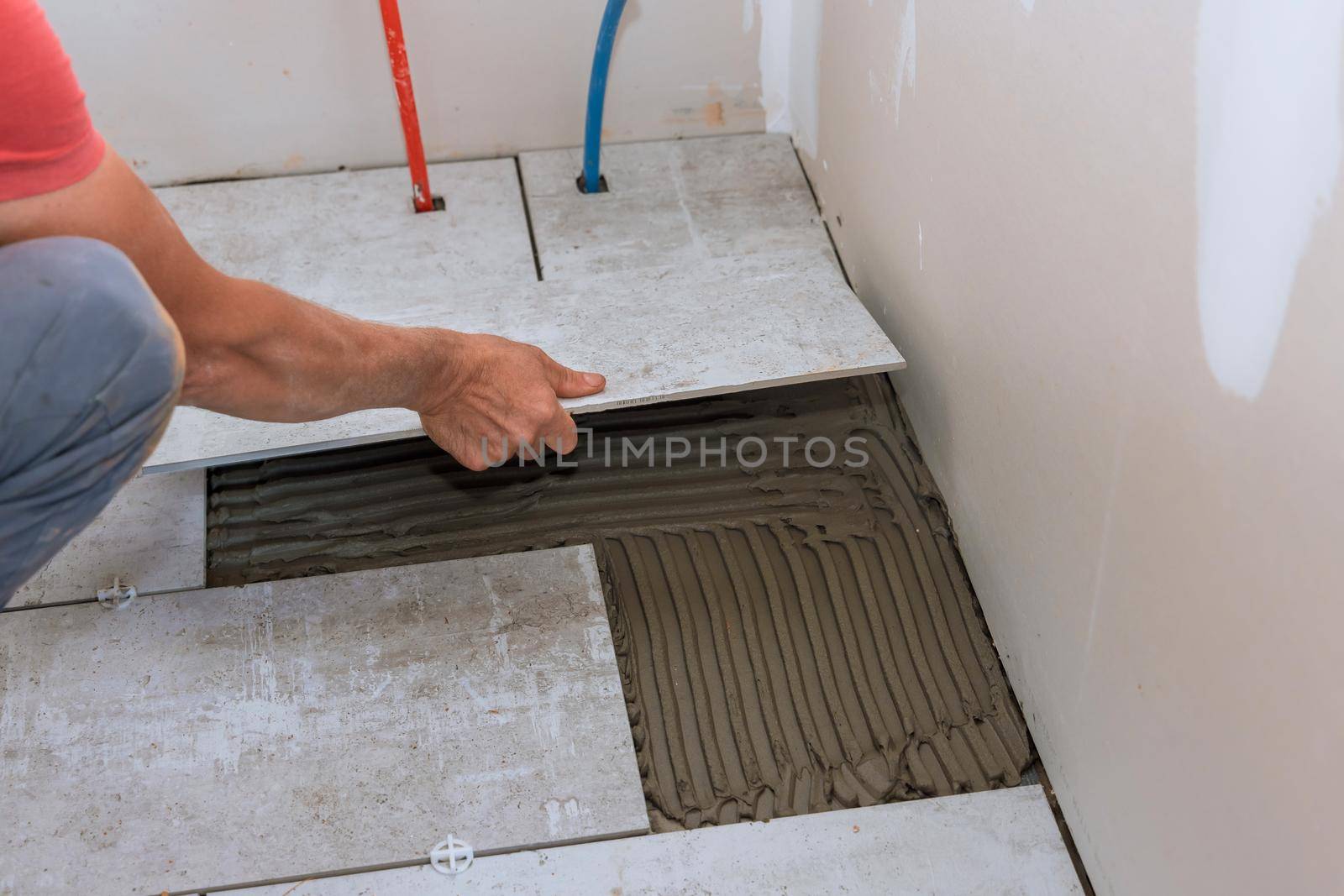 Placing ceramic floor tiles on adhesive surface with home construction working