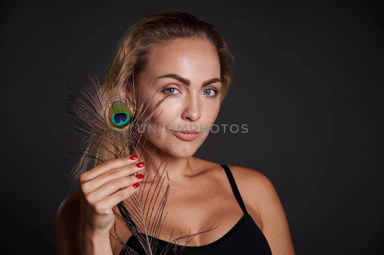 Beautiful Caucasian woman in black underwear holding a peacoch feather