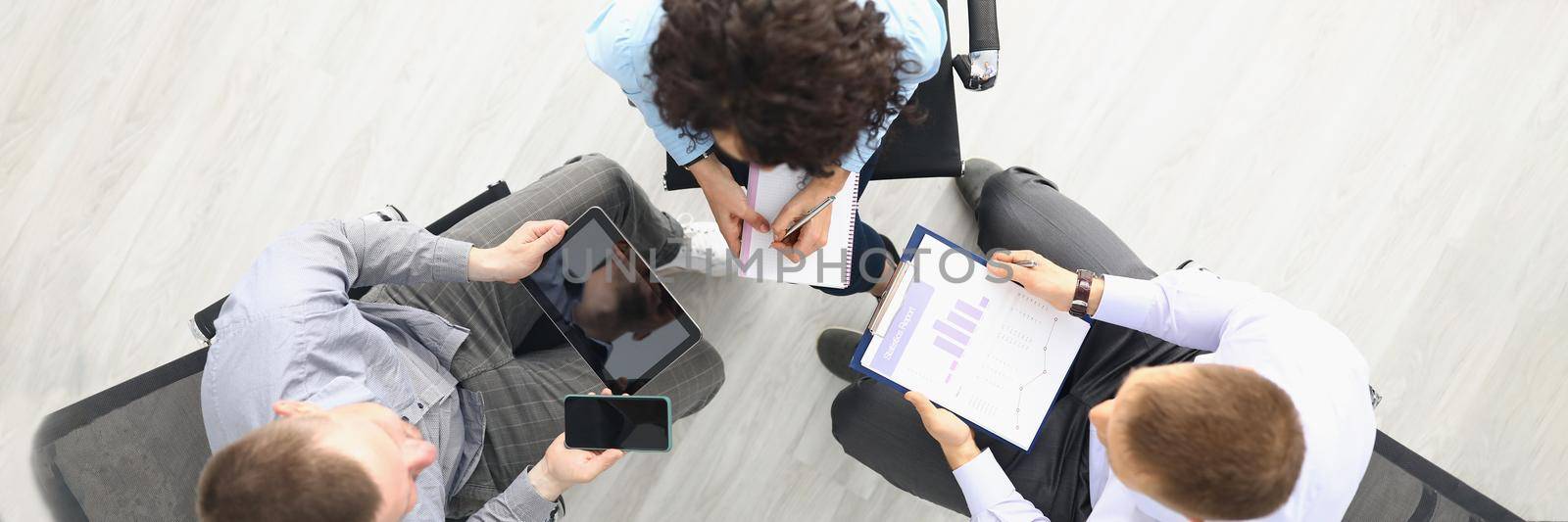 Top view of team having meeting to solve company problems, preparing report on finished projects. Creative workers with devices. Teamwork, job, office life, business concept