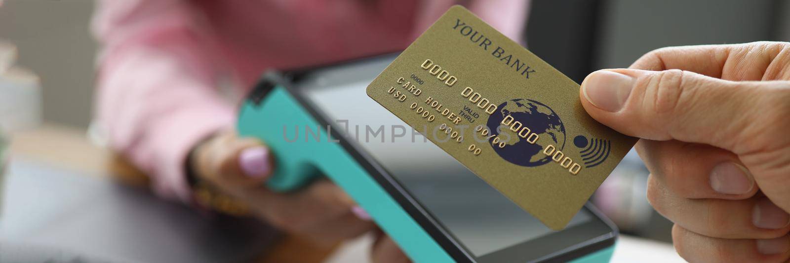 Close-up of customer holding credit card near nfc technology on counter, contactless payment for bill at store or cafe. Modern technology, transaction, cashier machine concept