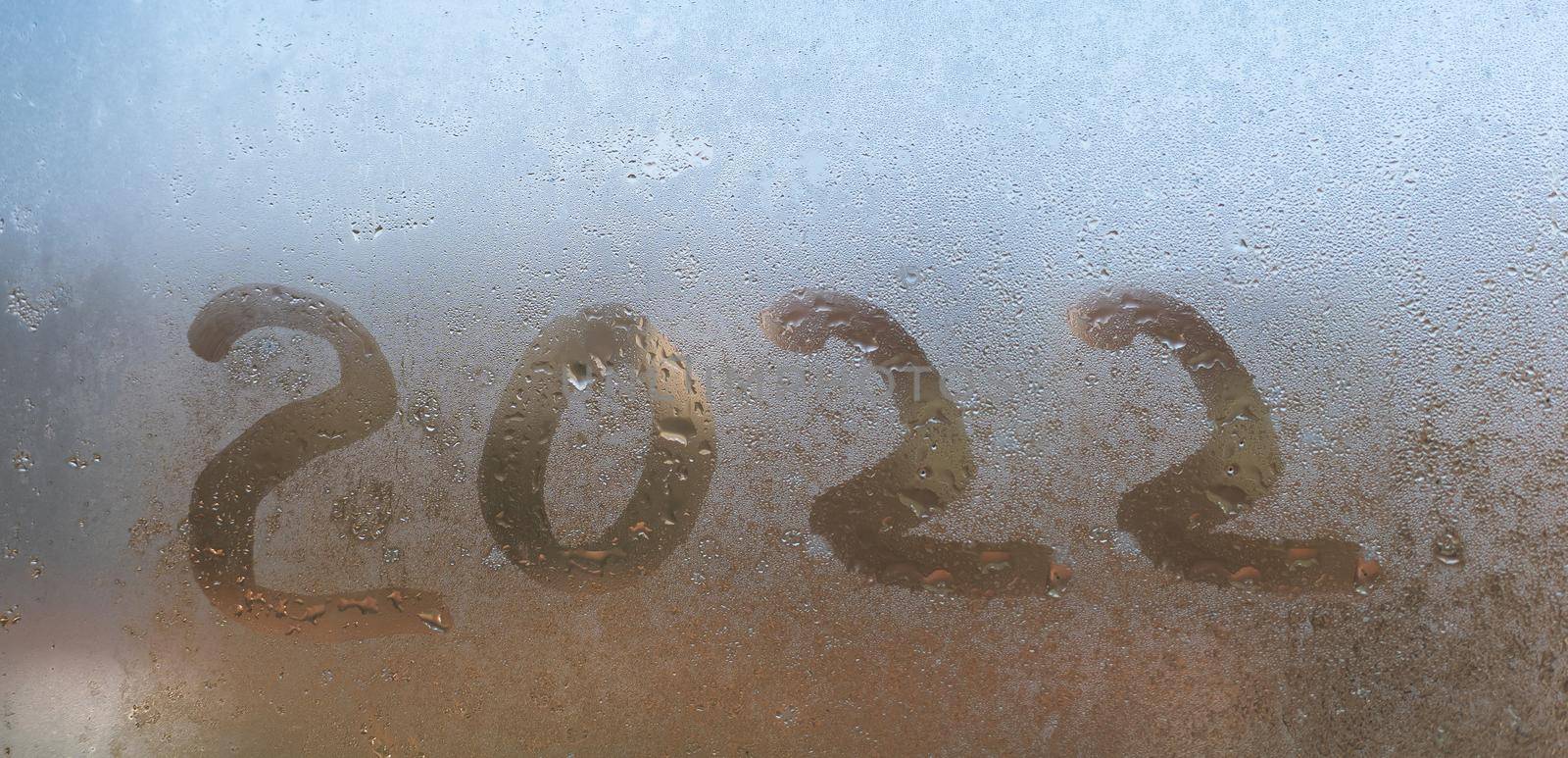 Handwritten word 2022 on a foggy window.