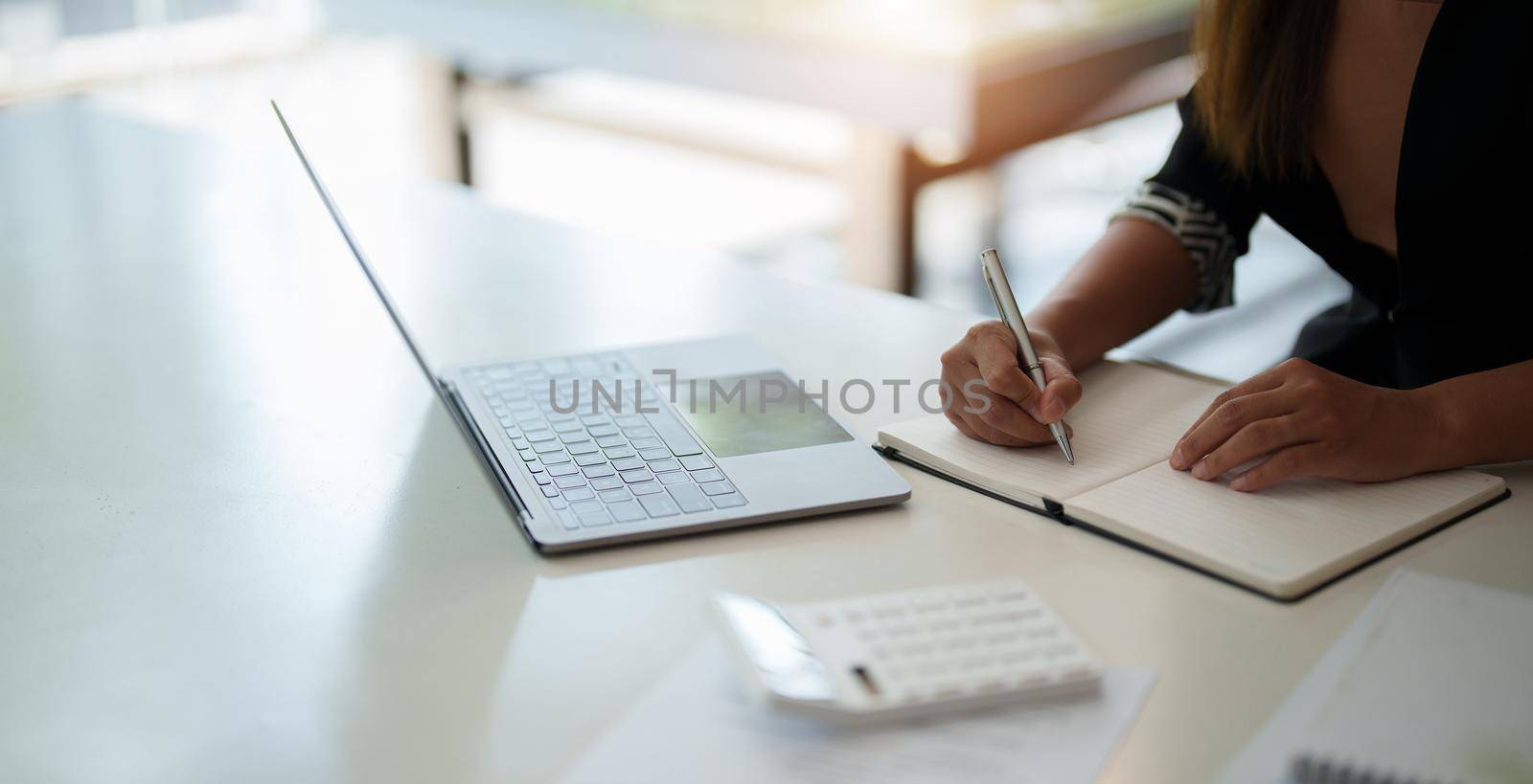 Cropped photo of woman writing making list taking notes in notepad working or learning on laptop indoors- educational course or training, seminar, education online concept.