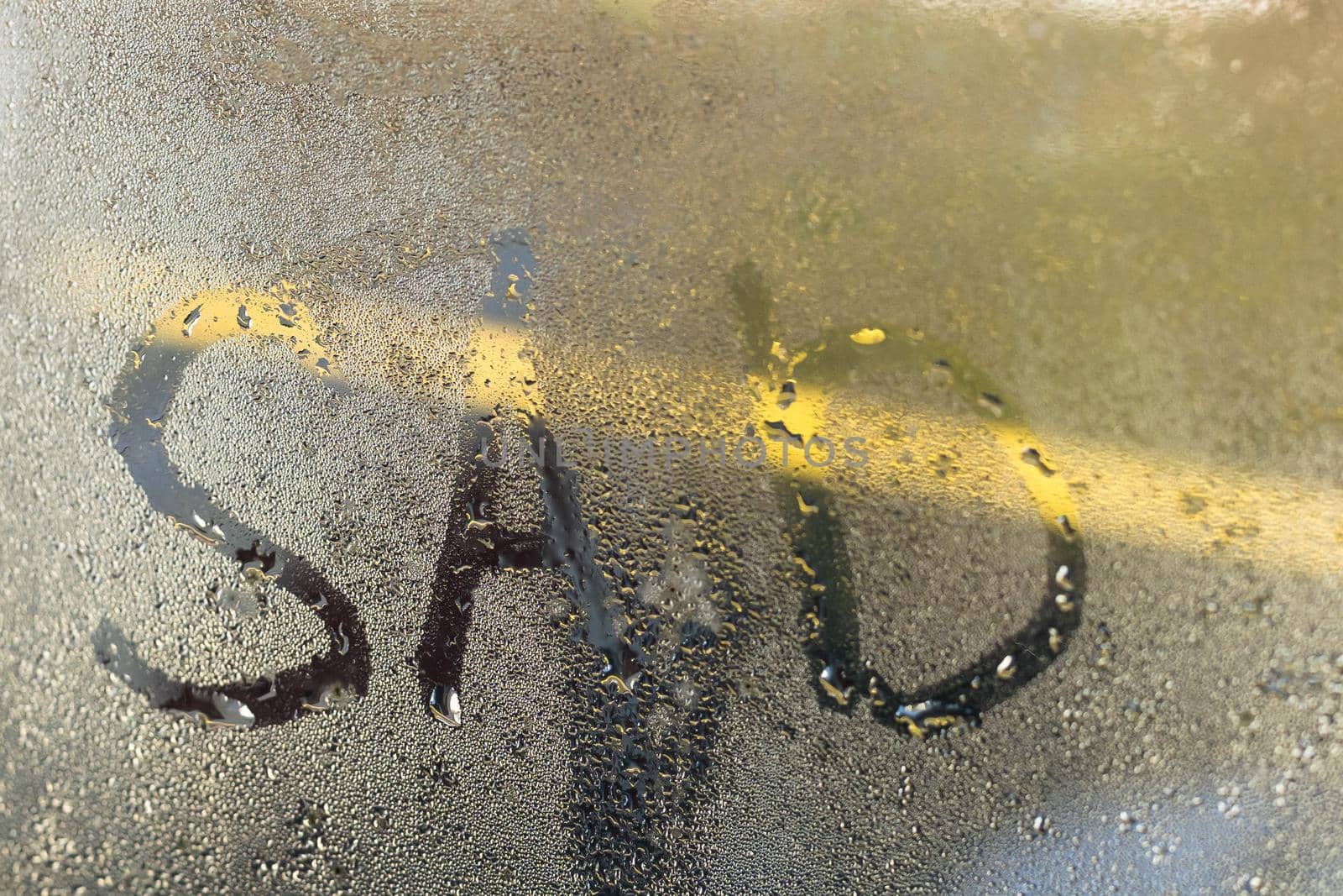 Inscription a sad written on wet window after rain.