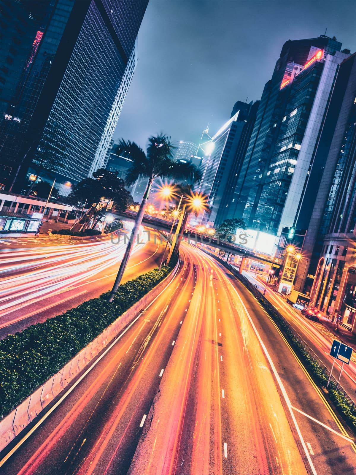 Street traffic in Hong Kong at night. Office skyscraper buildings and busy traffic on highway road with blurred cars light trails. Hong Kong, China