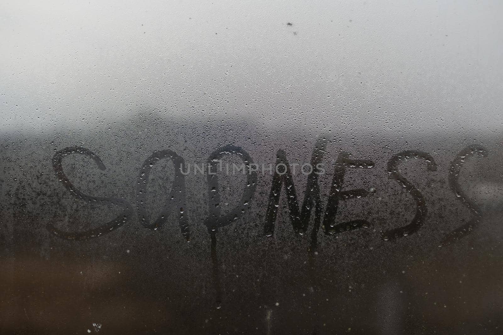 The inscription sadness on the wet window