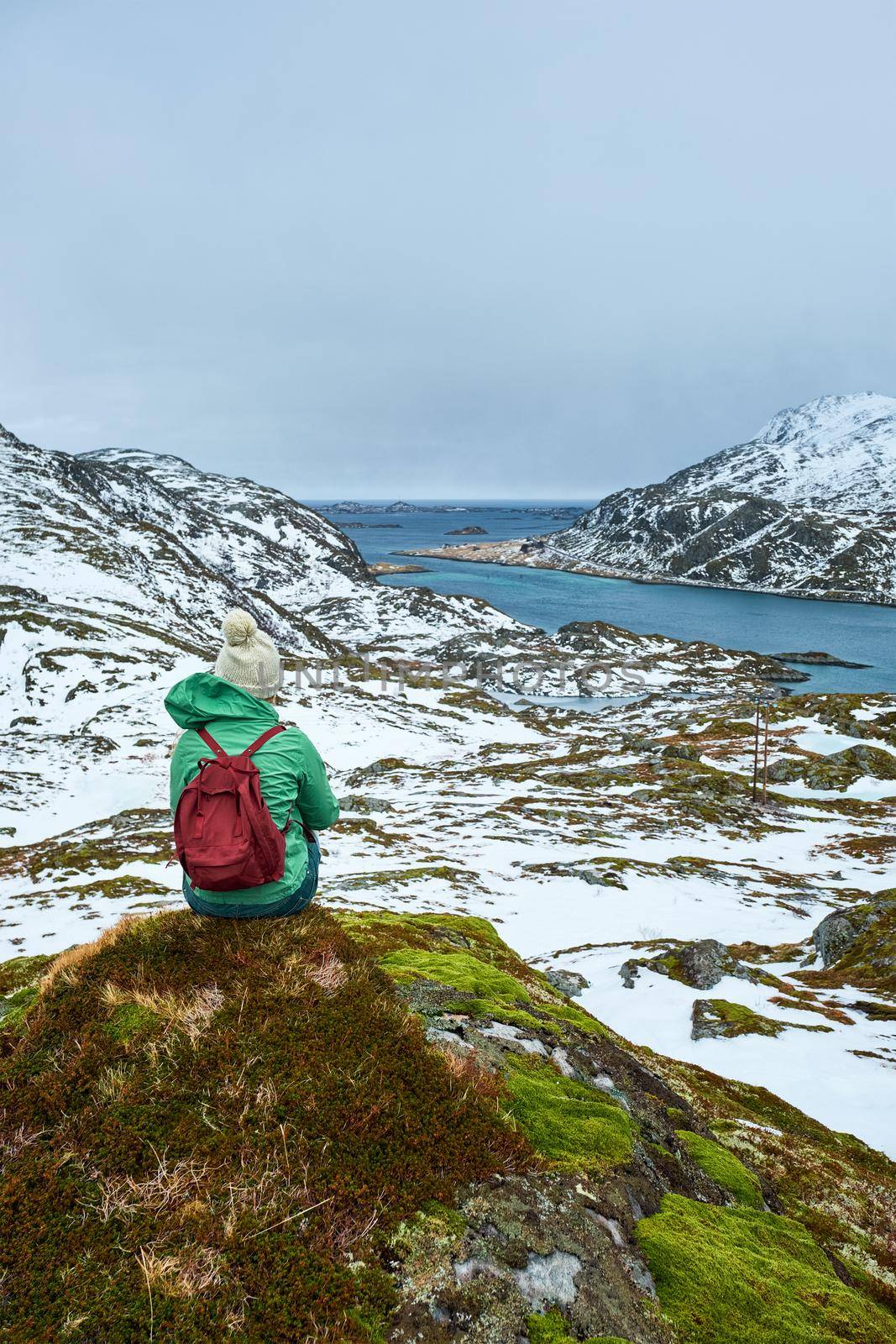 Woman tourist traveler enjoying a view of fjord in winter. Lofoten islands, Norway