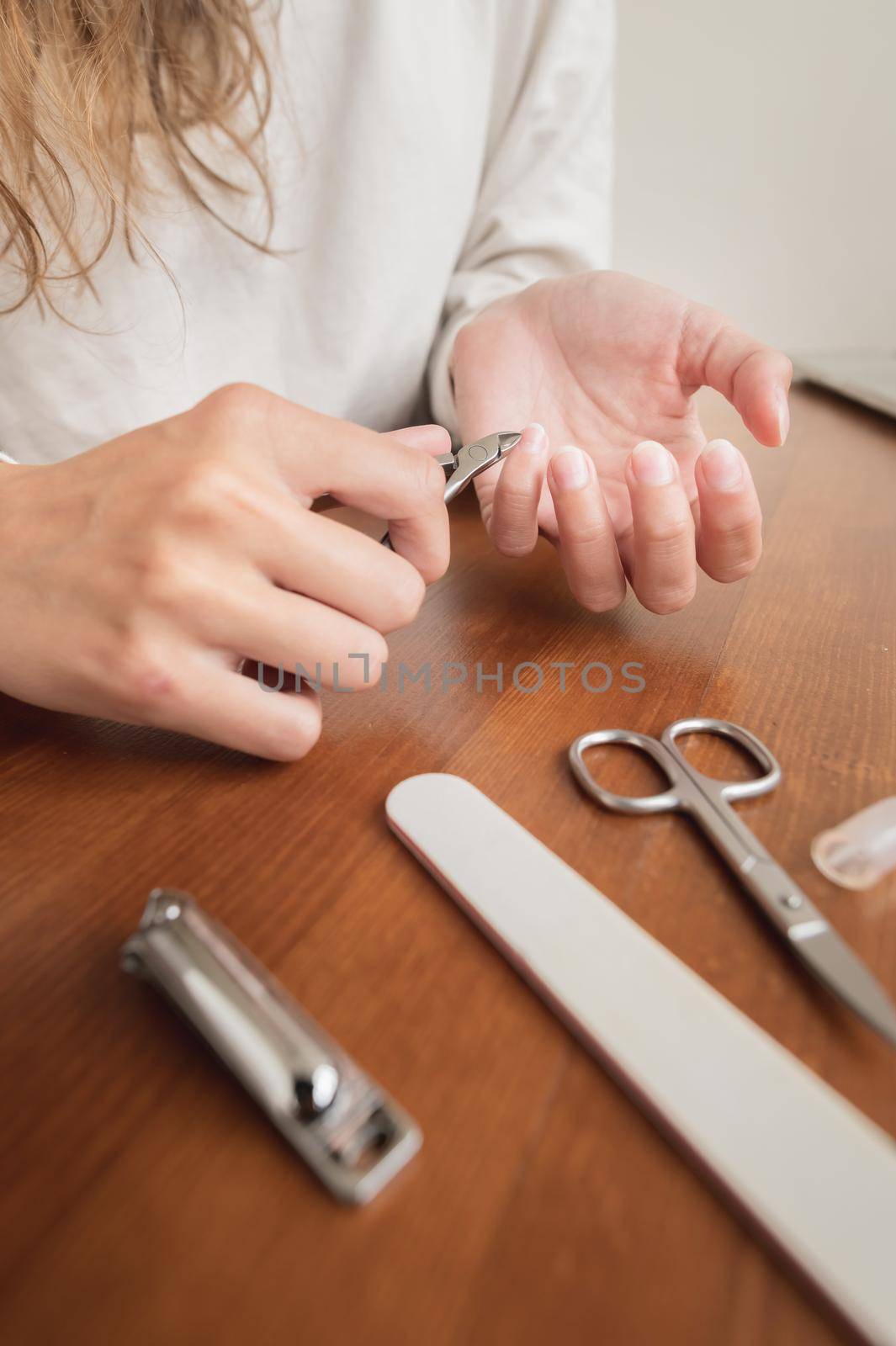 Close-up of hand of caucasian young woman doing manicure at home with nail supplies