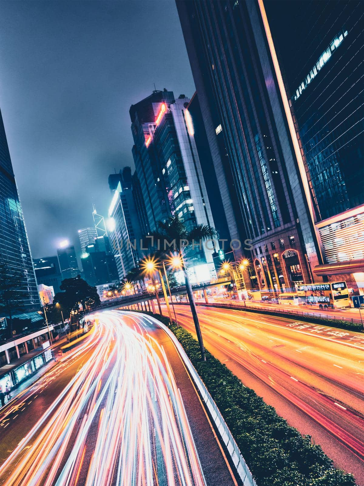 Street traffic in Hong Kong at night. Office skyscraper buildings and busy traffic on highway road with blurred cars light trails. Hong Kong, China