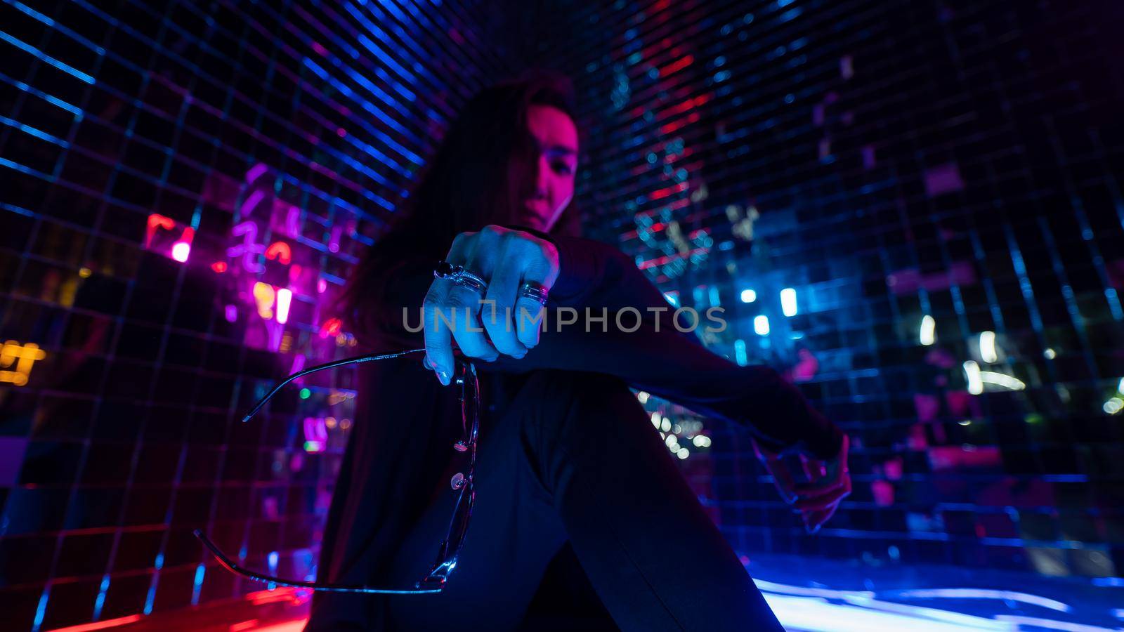 Asian man holding sunglasses. Neon photo studio