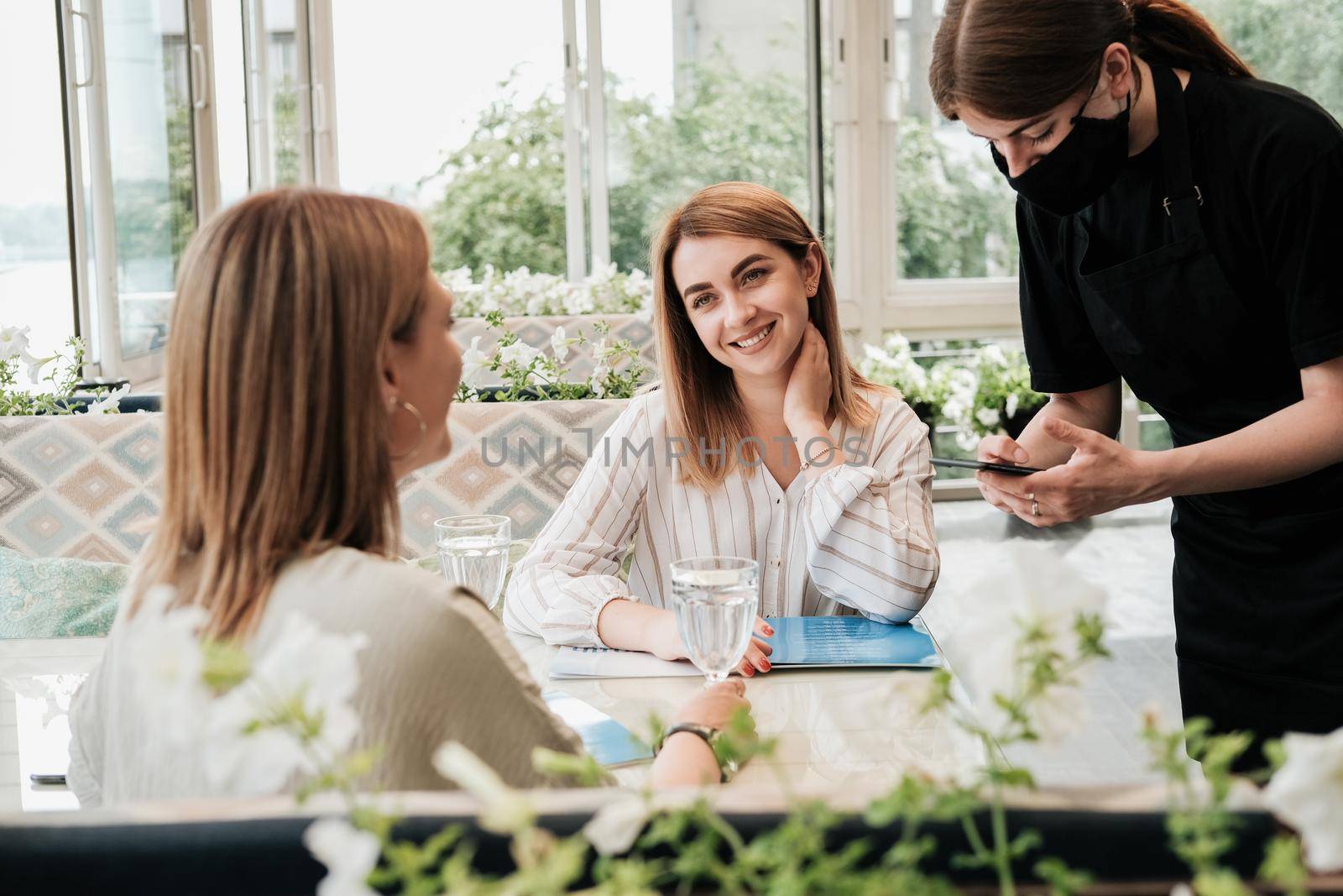 Two Women Sitting in the Restaurant and Making Order to Waiter