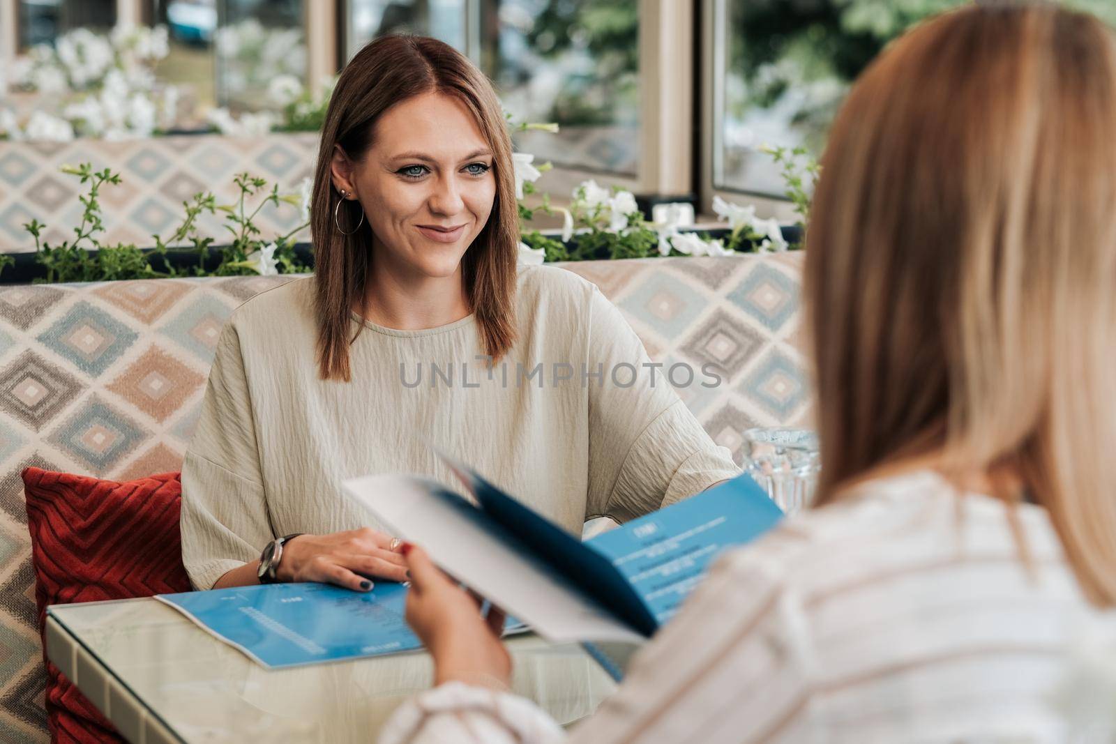 Two Women Sitting in Restaurant and Reading the Menu, Females on Lunch Meeting by Romvy
