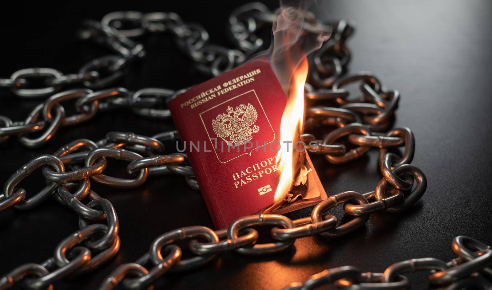 Russian passport is on fire against the background of a metal chain by Rotozey