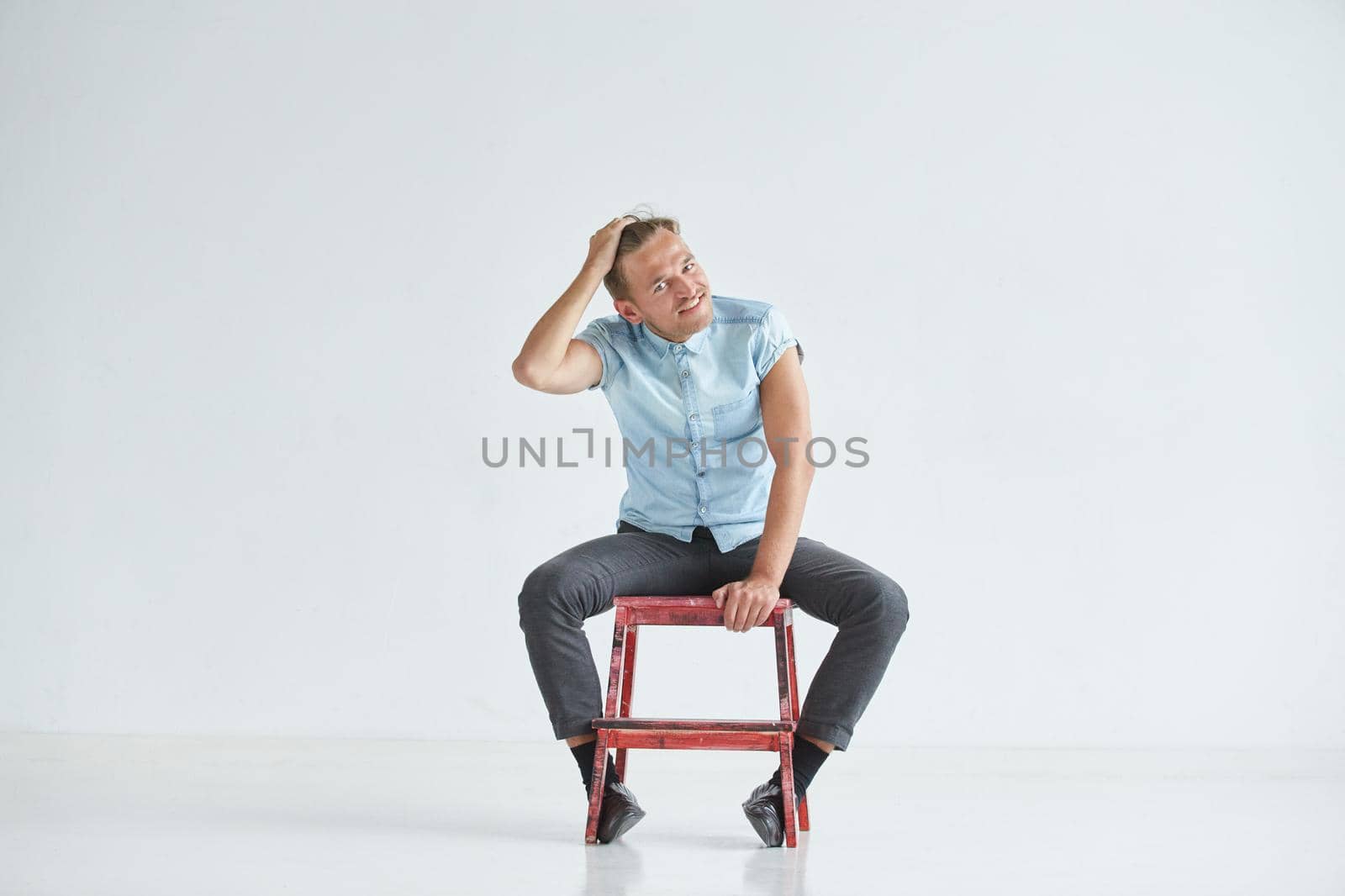 Brutal man in a shirt with short sleeves sitting in the chair, his fists clenched, slightly bent, under the gaze of the forehead. High quality photo