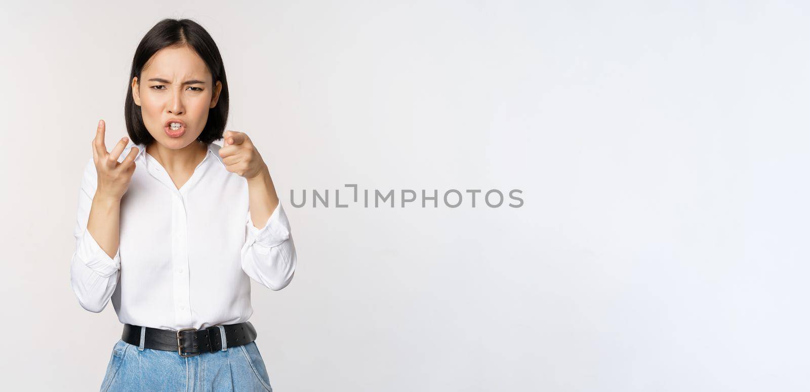 Image of angry pissed off woman shaking from anger, clench hands and grimacing furious, annoyed and outrated, standing over white background.