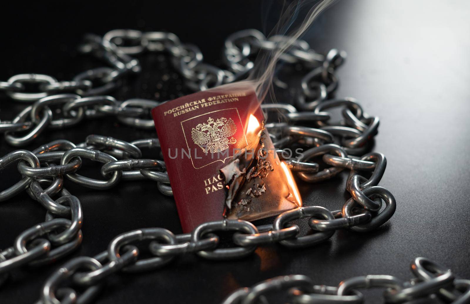 Russian passport is on fire against the background of a metal chain by Rotozey