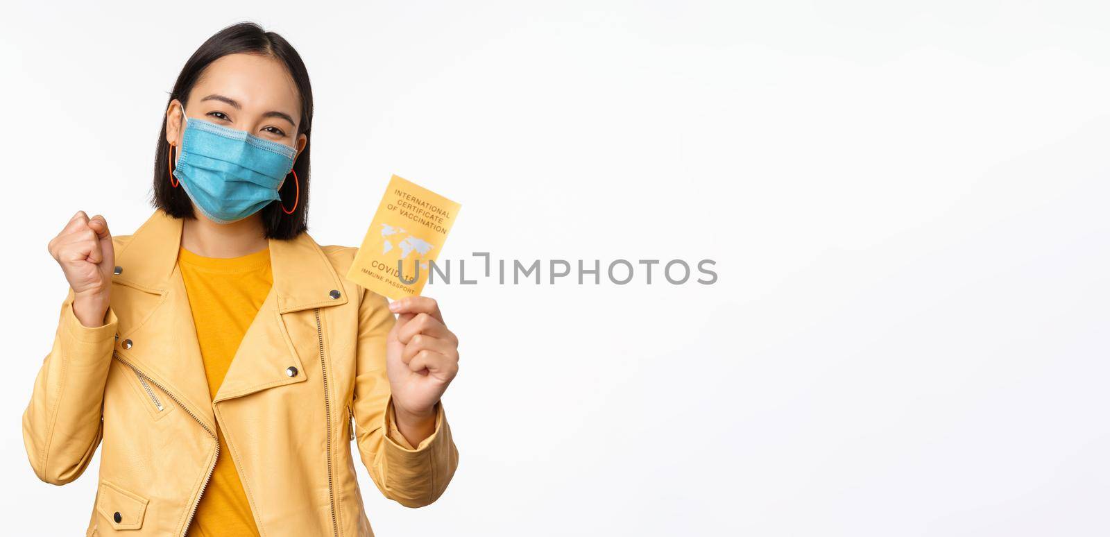 Hey you got point. Cheerful cute asian lively girl dark short haircut pointing camera finger-pistol smiling broadly, encourage friend make move, congratulate coworker good job, stand blue background.