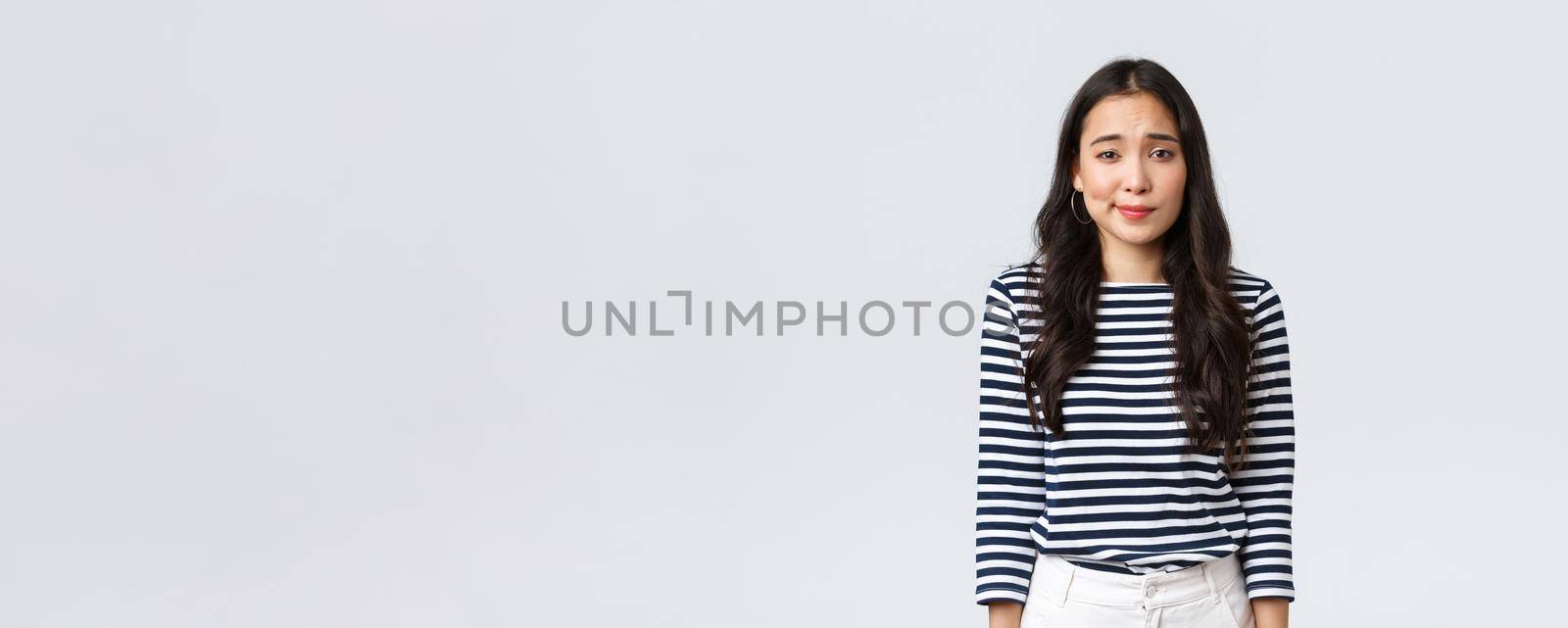 Lifestyle, people emotions and casual concept. Shy and modest cute clueless girl, smirk and looking camera uncertain, having doubts or hesitations, standing white background.