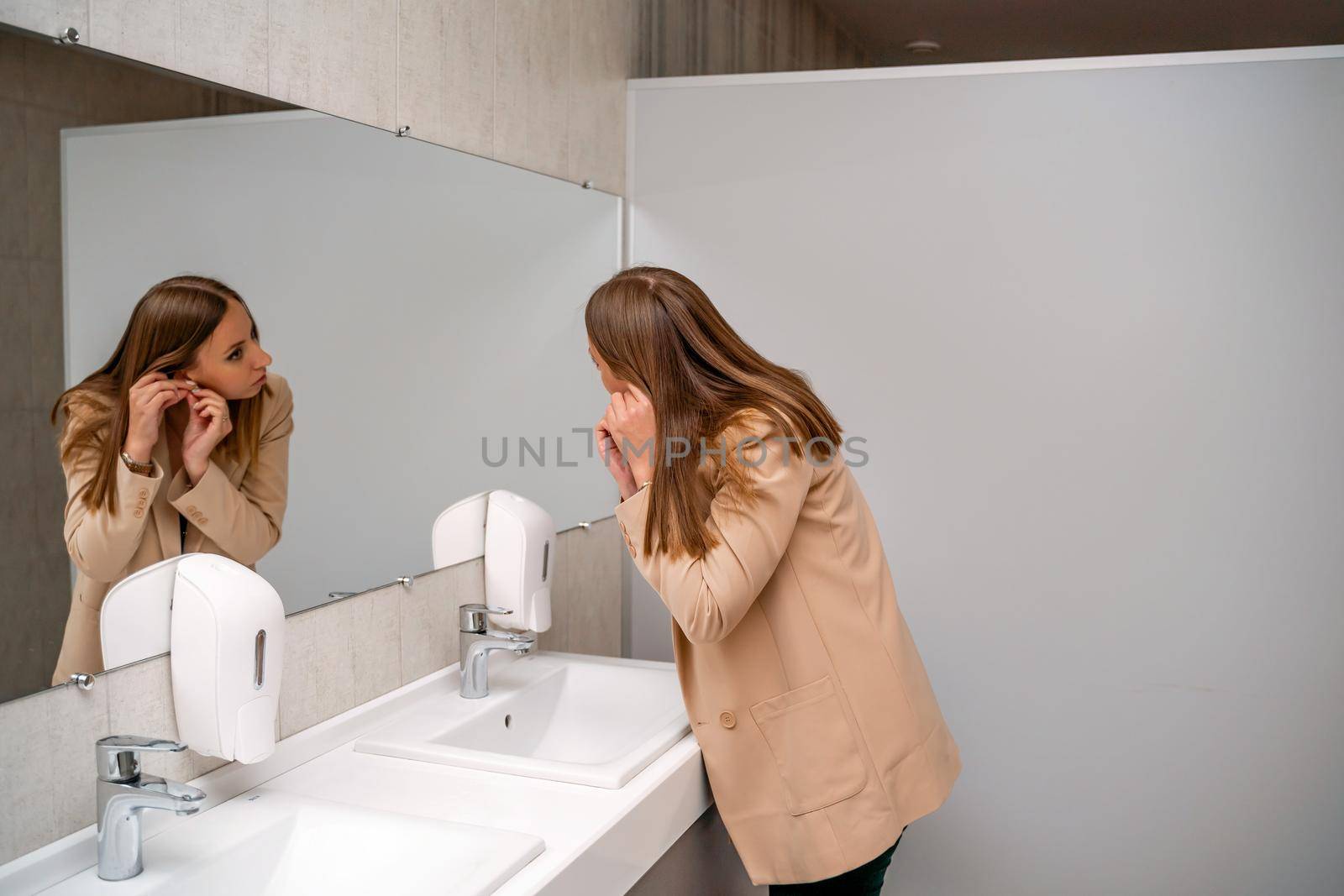 A woman washes her hands under running tap water in a public toilet