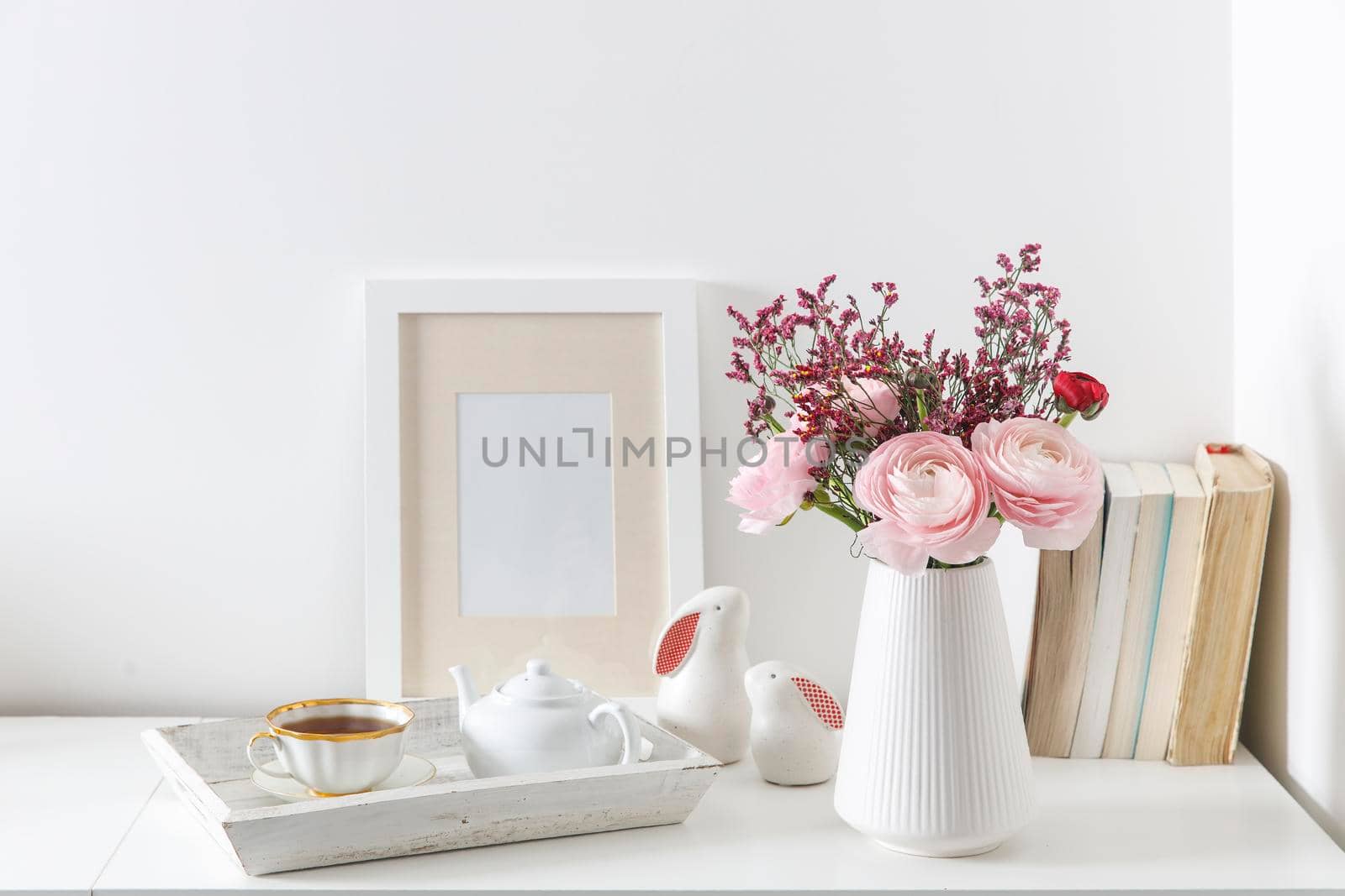 Bouquet of red and pink Persian buttercups on a white table. Scandinavian style. Place for text. Copy space by elenarostunova