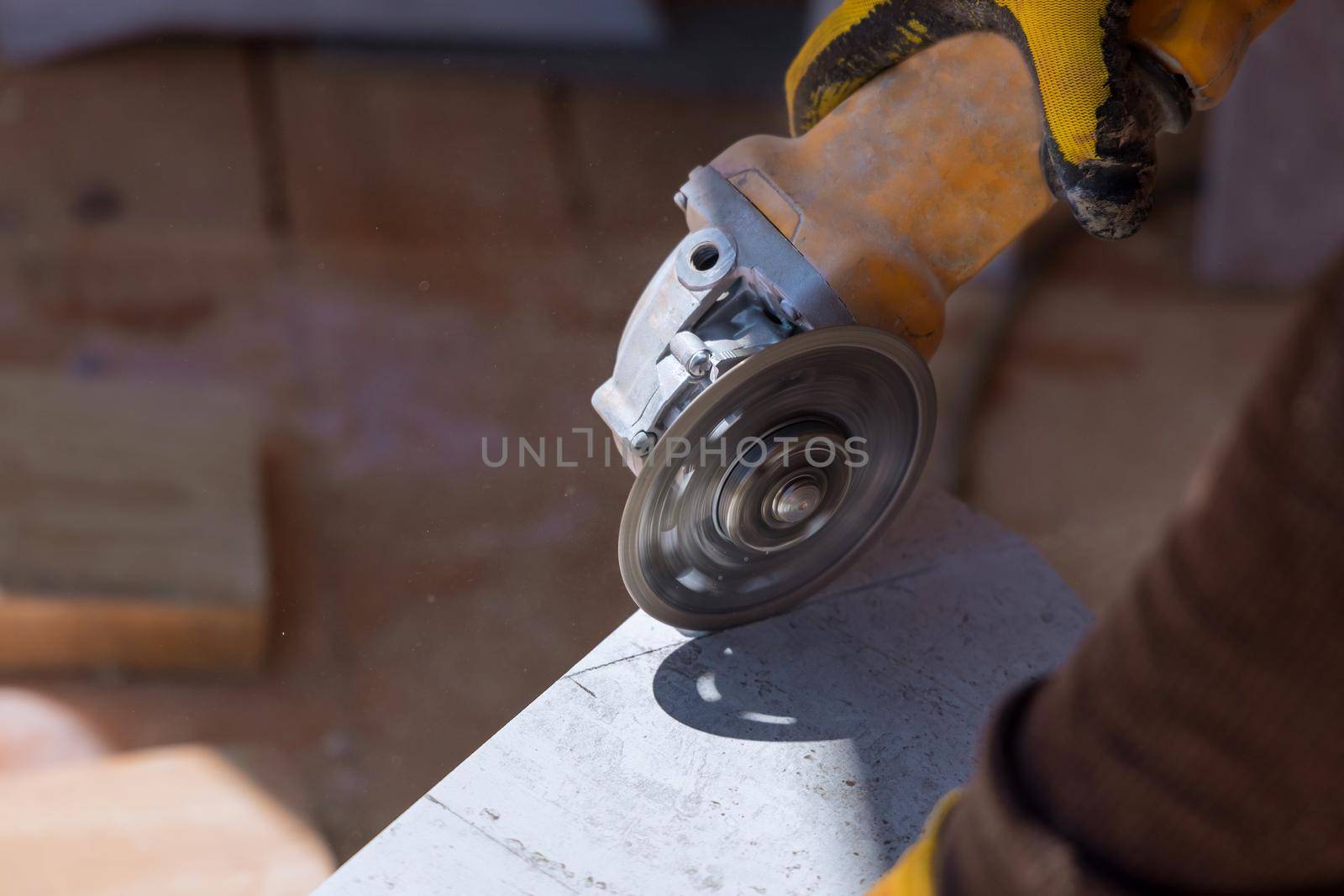 Construction worker cuts the tiles with a special tool with a diamond disc