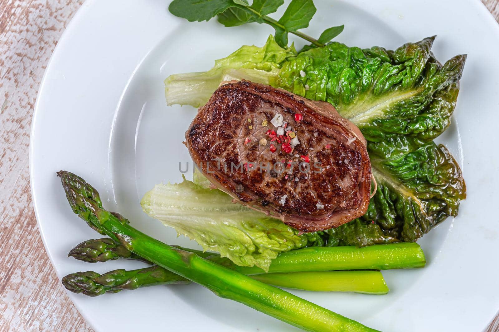 Close-up of a roasted tournedos placed on cooked leaves - top view