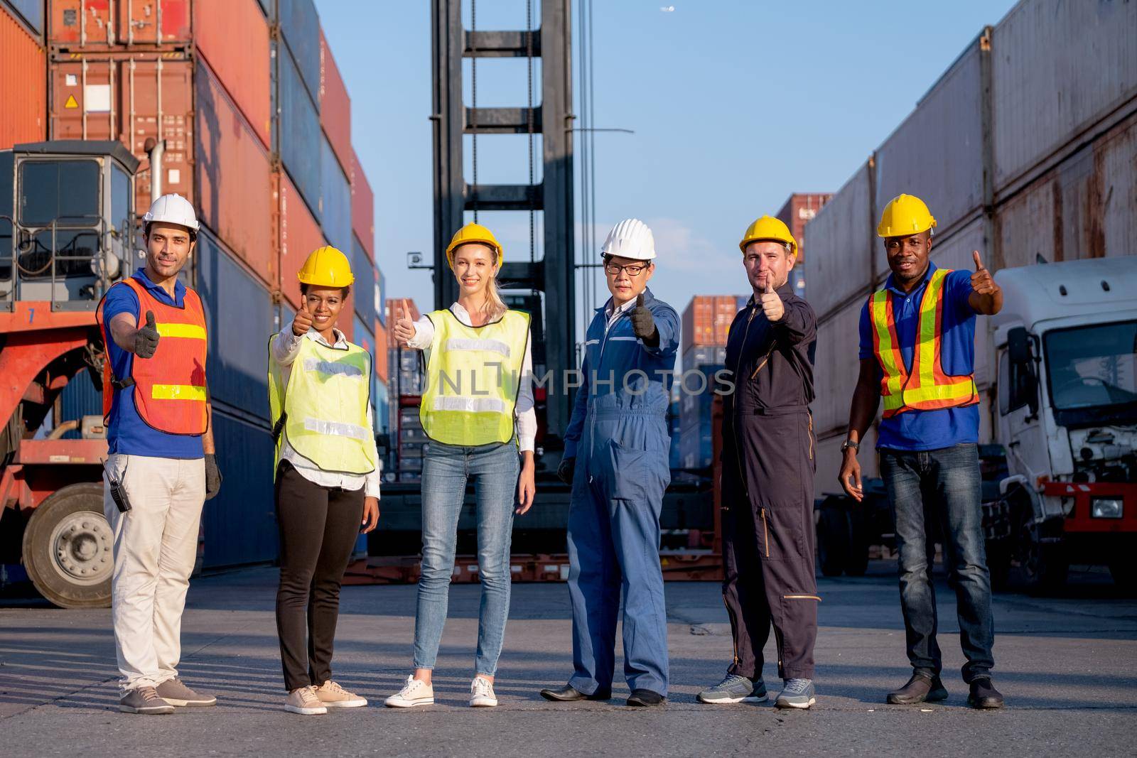 Group of foreman and cargo container workers or technician stand in row and show thumbs up to camera for symbol of successful in delivery and transport system business. by nrradmin