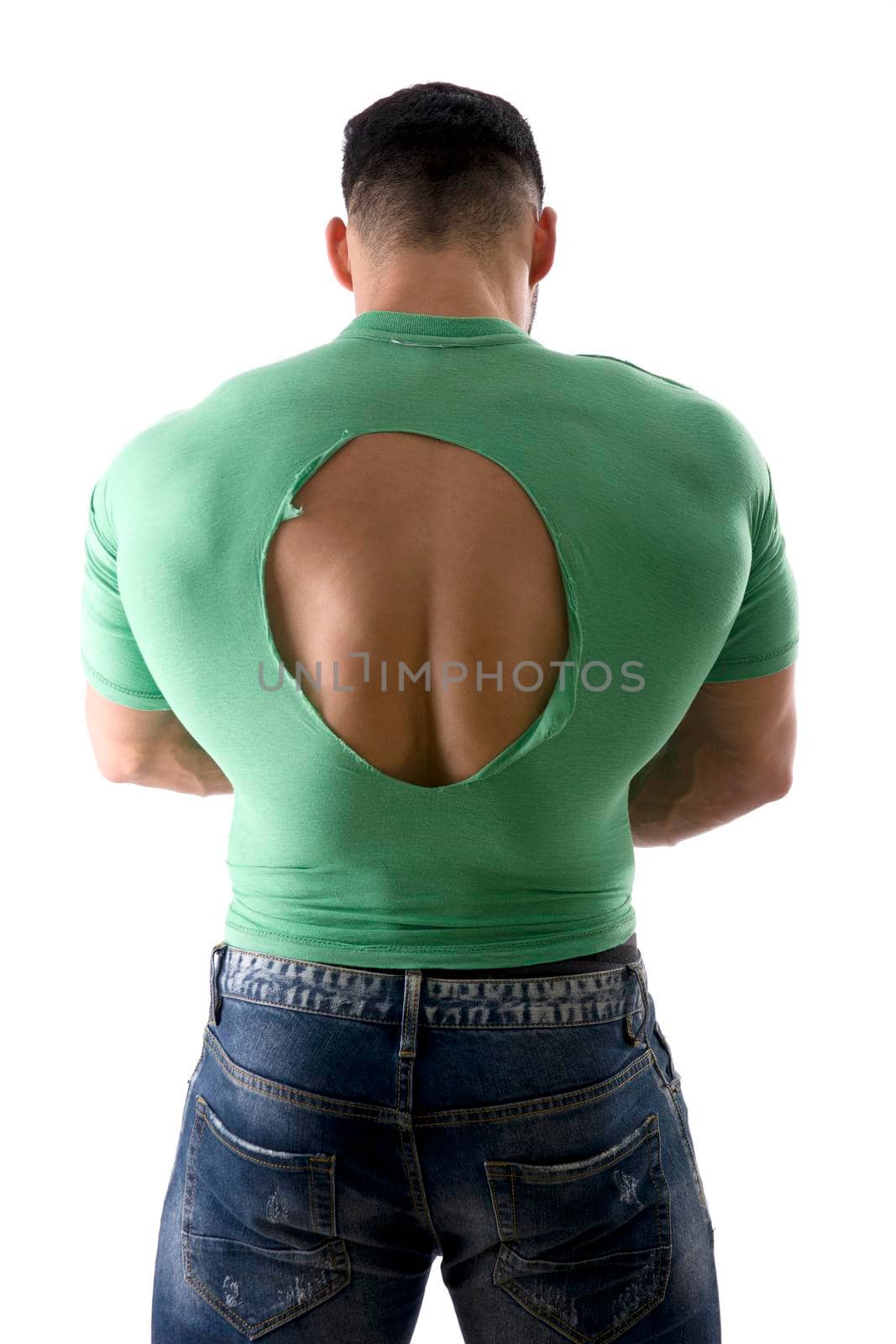 Back view of anonymous muscular male in torn t shirt standing on white background in studio and demonstrating power