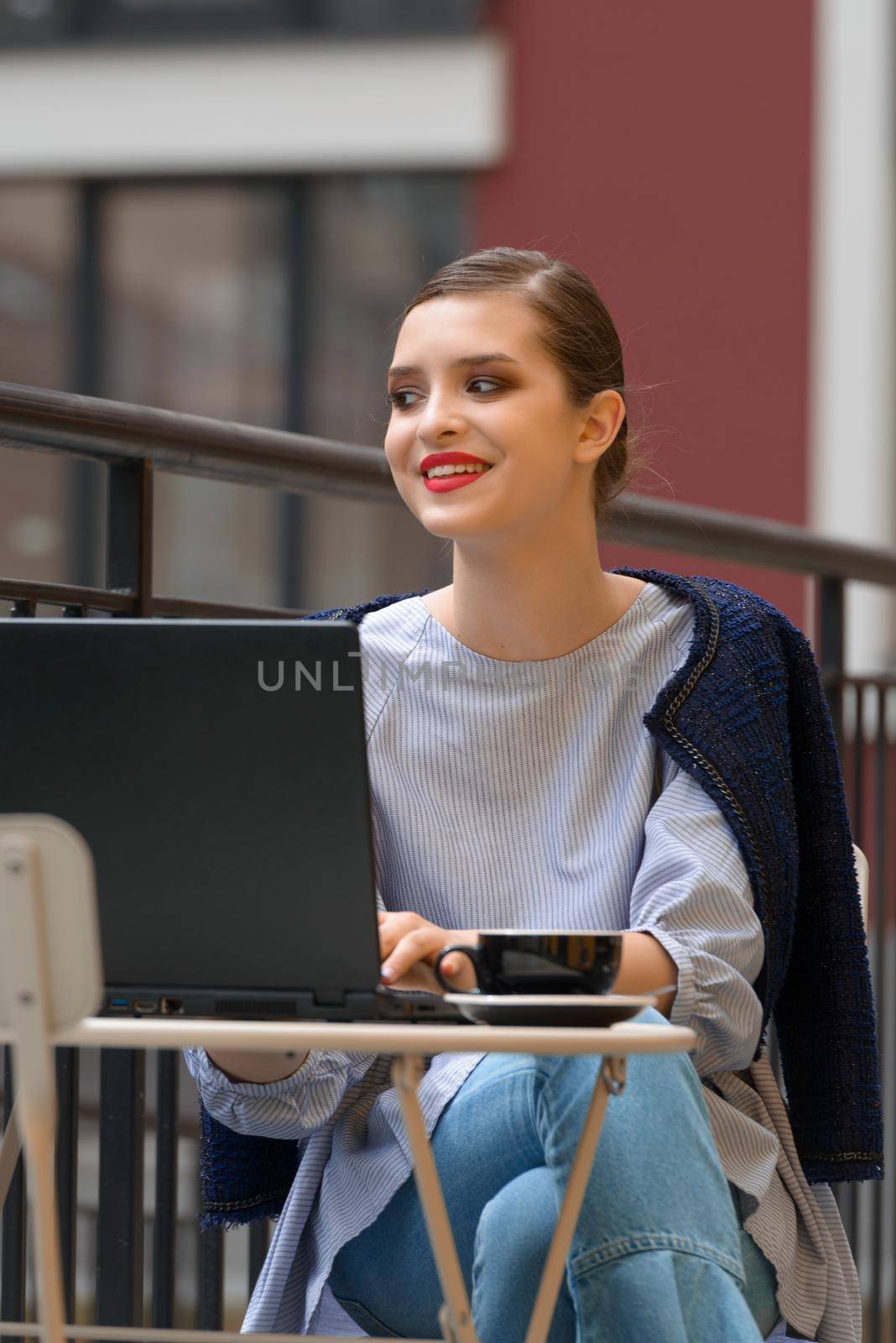 Charming happy woman student sitting in a cafe and using laptop computer to prepare for the course work. by Ashtray25