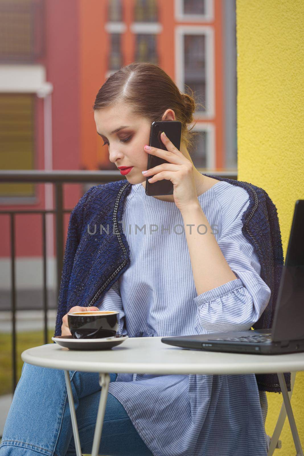 Charming happy woman student communicates by phone and use laptop computer to prepare for the course work. by Ashtray25