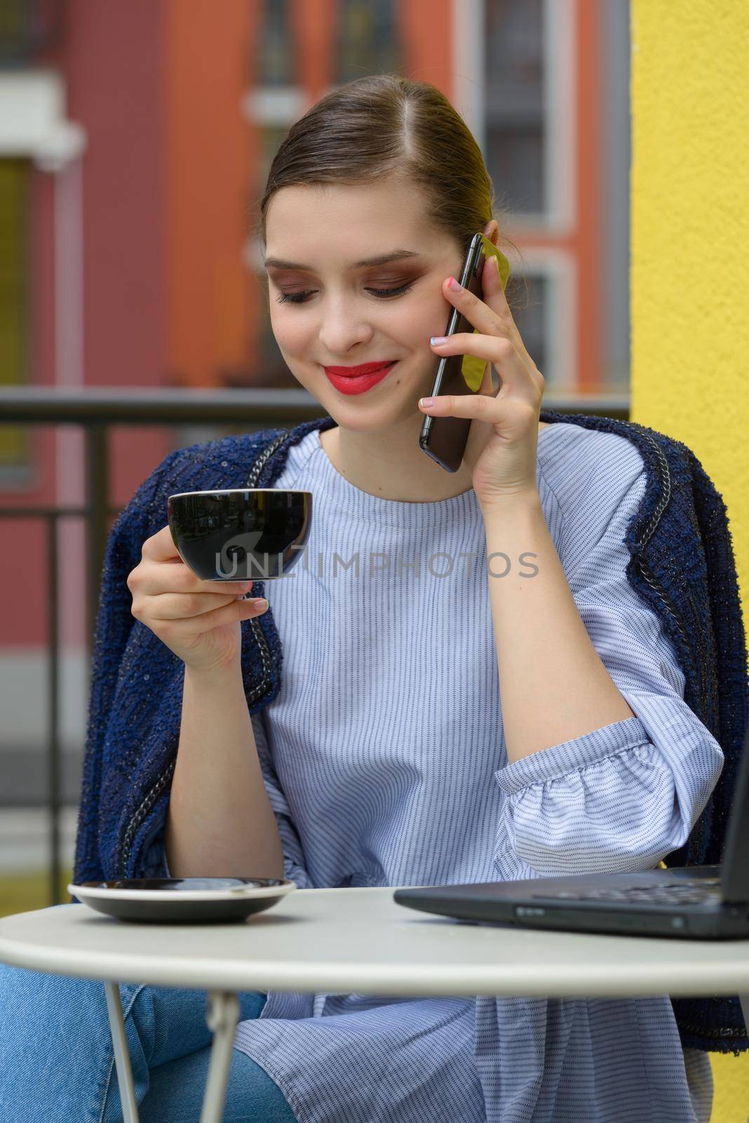 Charming happy woman student communicates by phone and use laptop computer to prepare for the course work. by Ashtray25