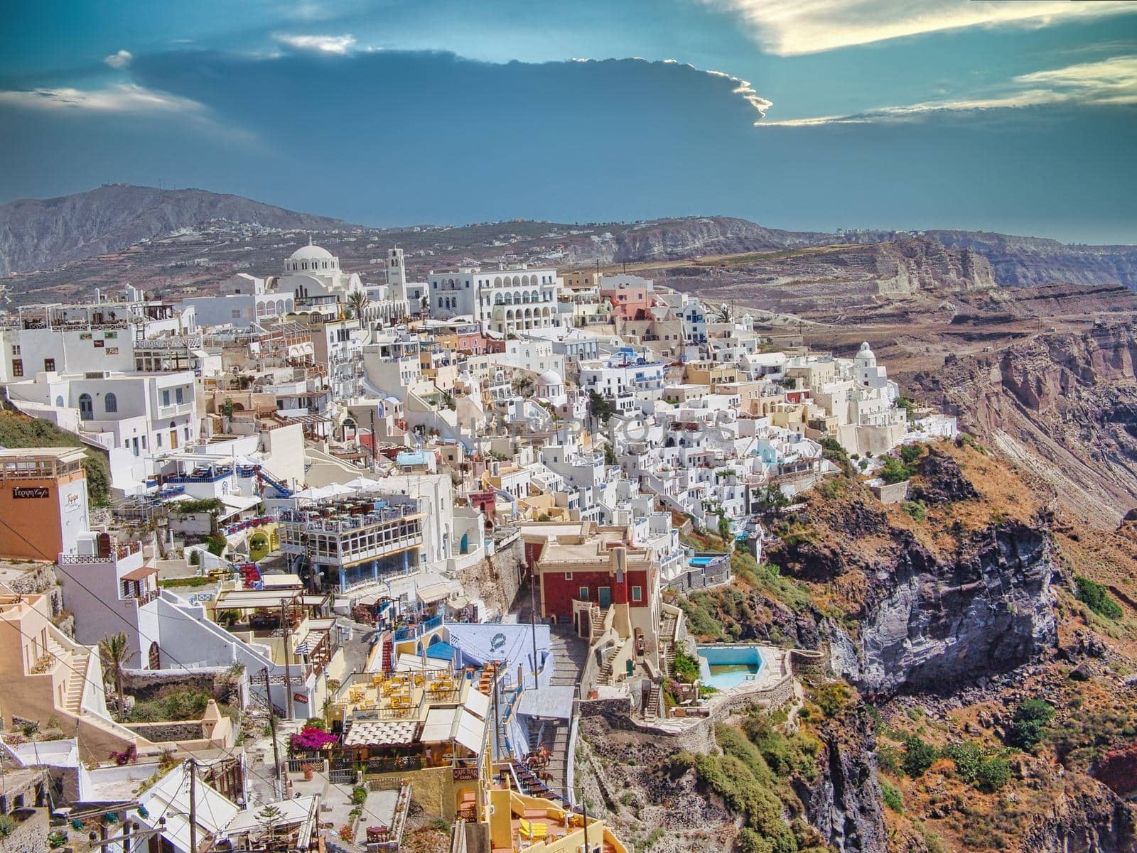 Fira, Santorini - Greek Islands landmark with white village, cobbled paths, greek orthodox blue church and sunset over caldera. Cyclades, Greece