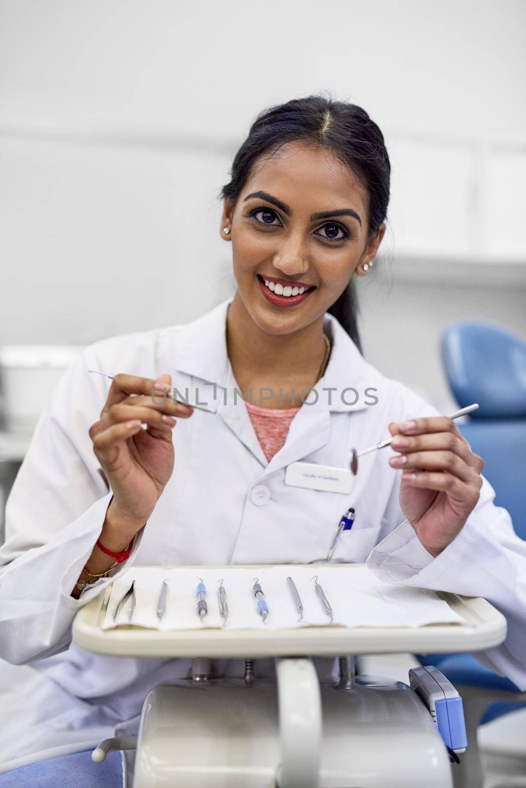 Portrait of a young female dentist working with surgical instruments in her office.