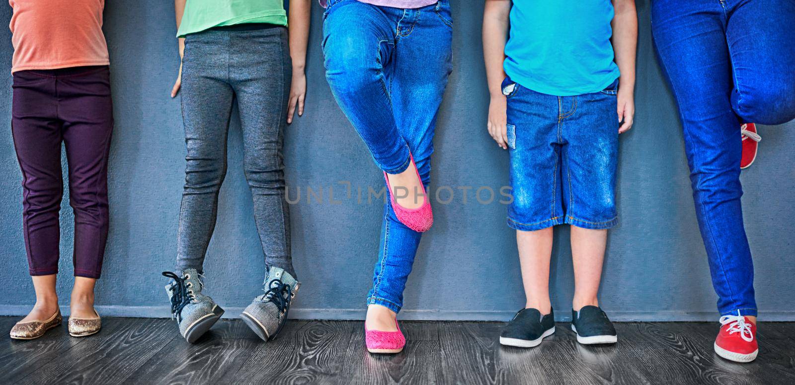 Stand in line, its the kids turn now. Cropped studio shot of a group of kids standing against a blue wall. by YuriArcurs