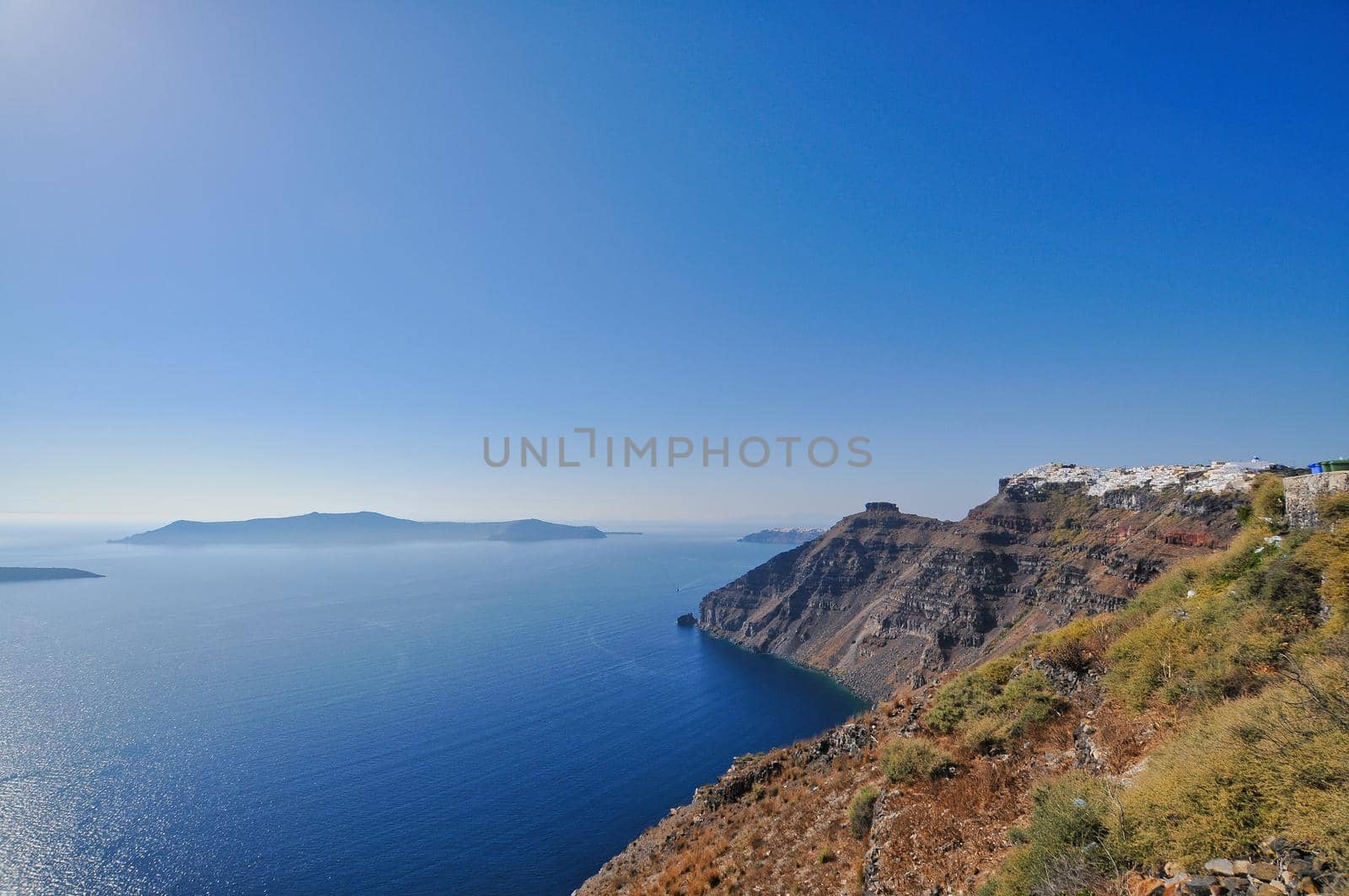 Scenic view of traditional cycladic Santorini houses on small street with flowers in foreground